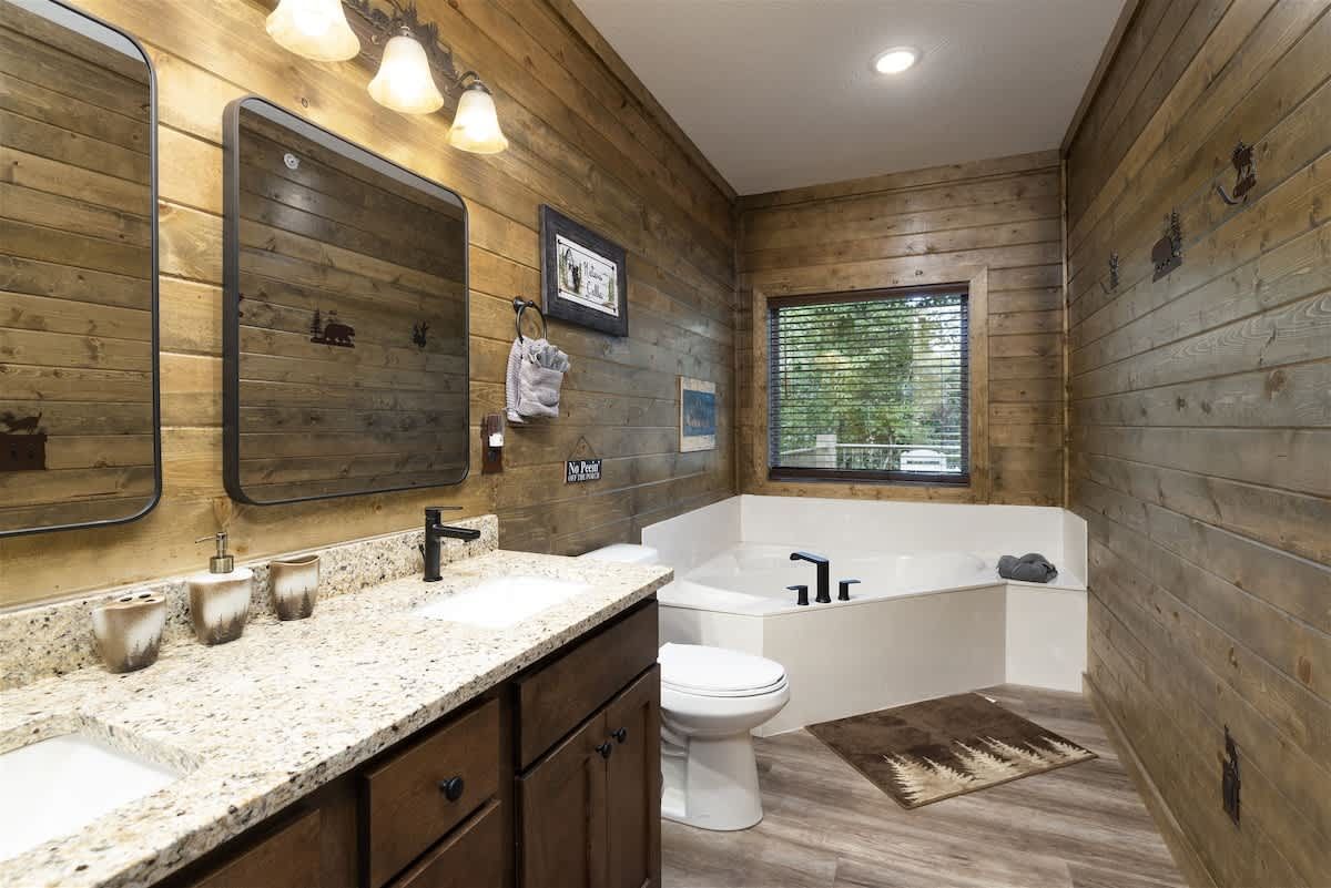 A bathroom with two sinks , a toilet , and a tub.