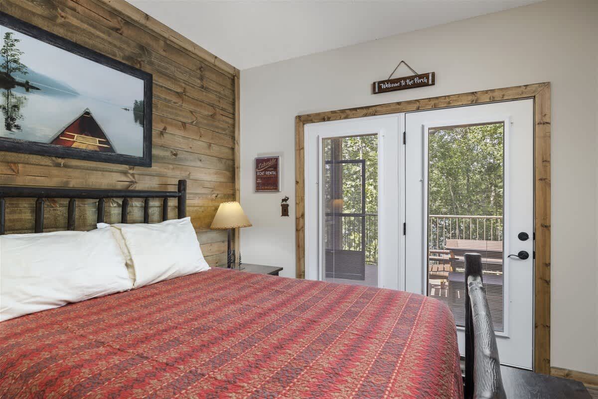 A bedroom with a king size bed and a sliding glass door leading to a balcony.