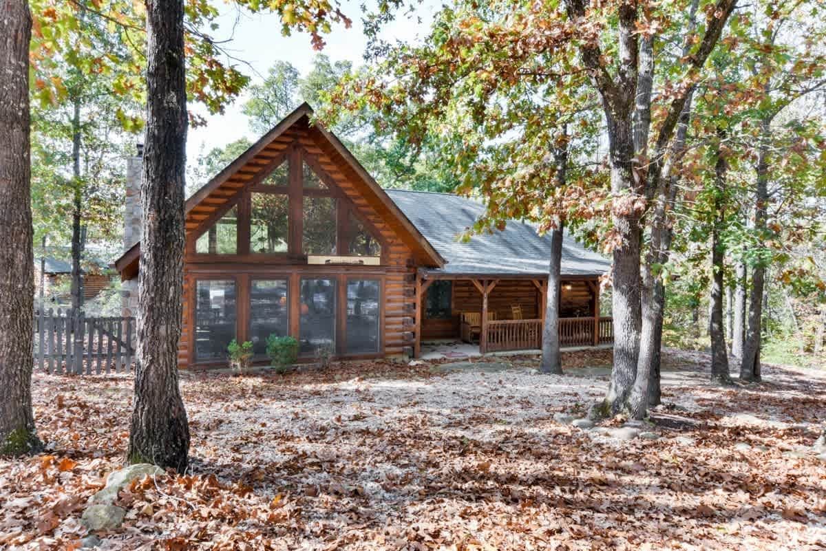 A large log cabin in the middle of a forest surrounded by trees.