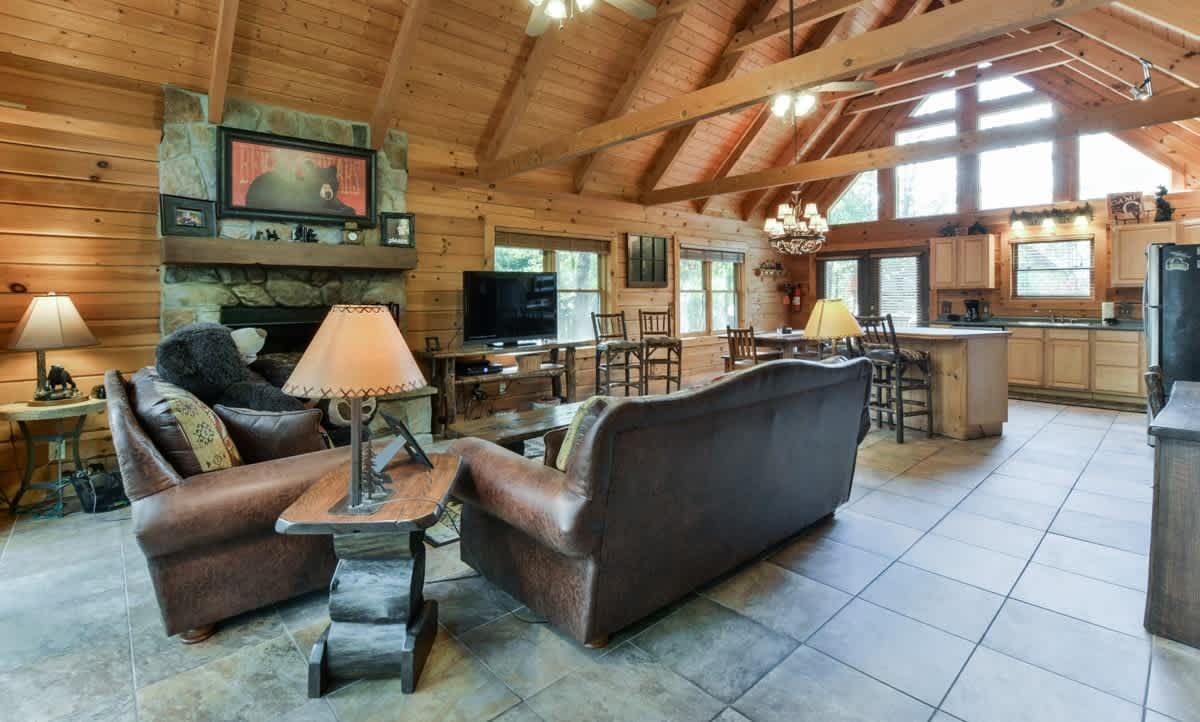 A living room filled with furniture and a fireplace in a log cabin.