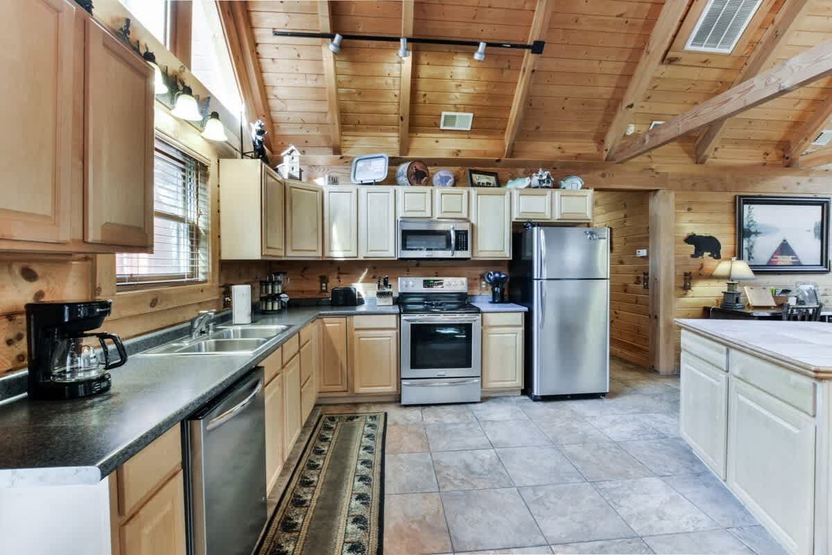 A kitchen in a log cabin with stainless steel appliances and wooden cabinets.