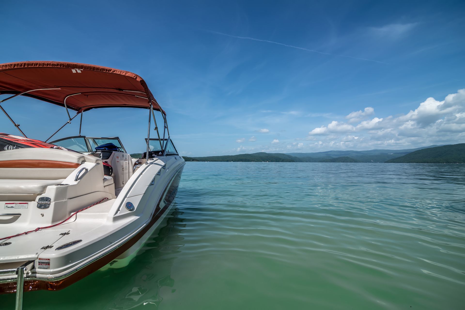 Boat on turquoise water, under a blue sky, with a red canopy.