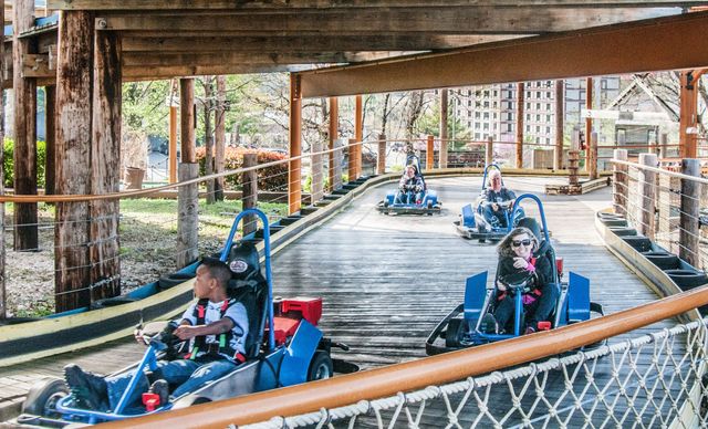 A group of people are riding go karts on a wooden track.