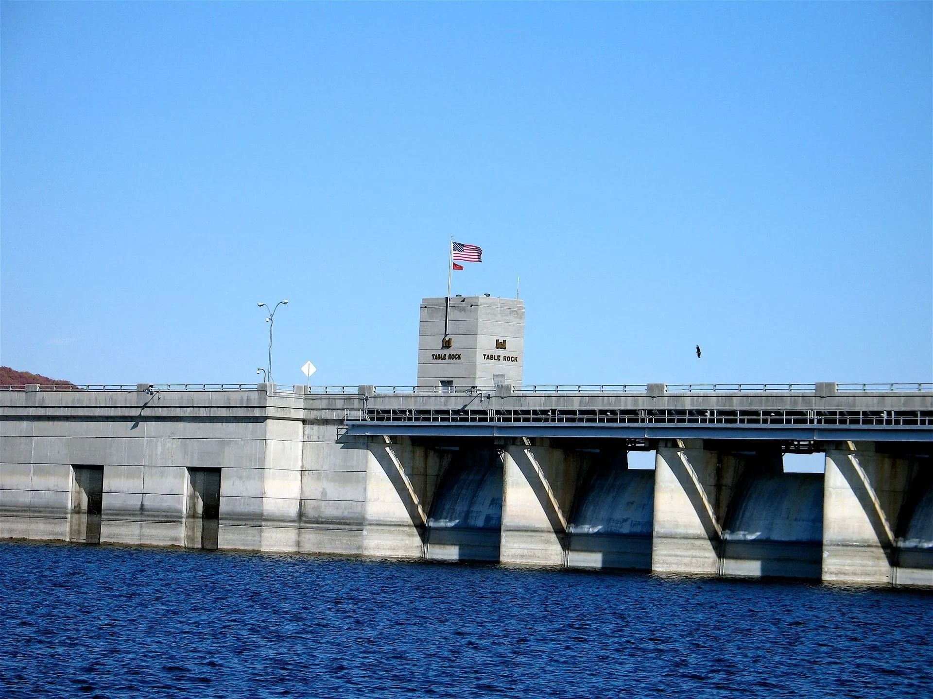 An american flag flies over a bridge over a body of water