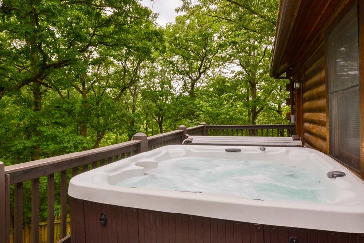 A hot tub is on the deck of a log cabin.