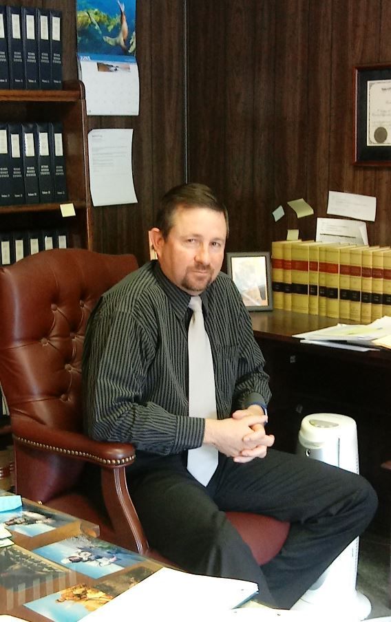 A man in a striped shirt and tie is sitting in a chair