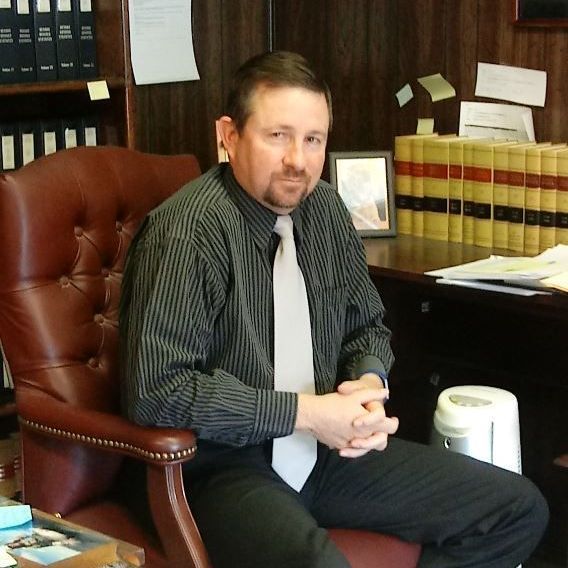 A man in a striped shirt and tie is sitting in a chair