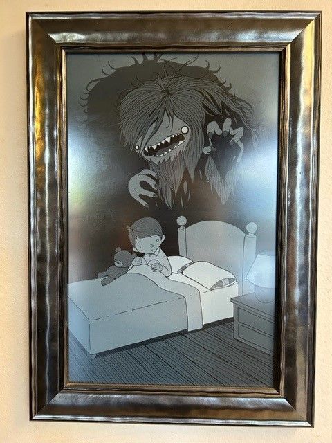 Framed black-and-white illustration of a child in bed startled by a large monster looming overhead.