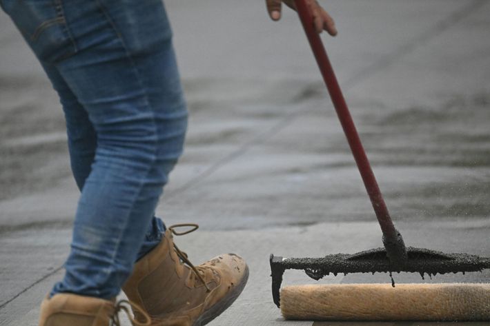 person pushing squeegee, leveling sealcoating solution
