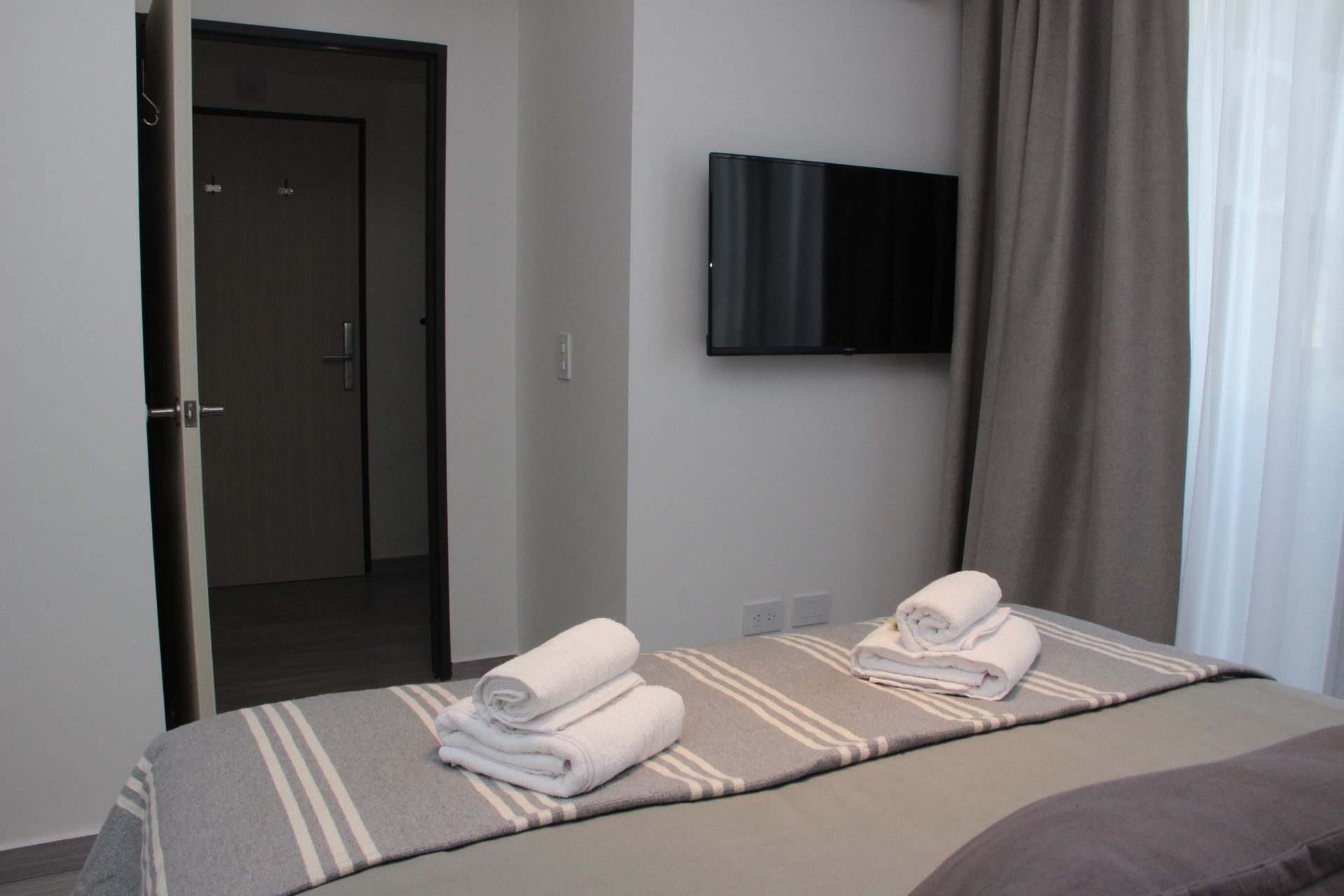 Un dormitorio con una cama y un televisor en la pared.