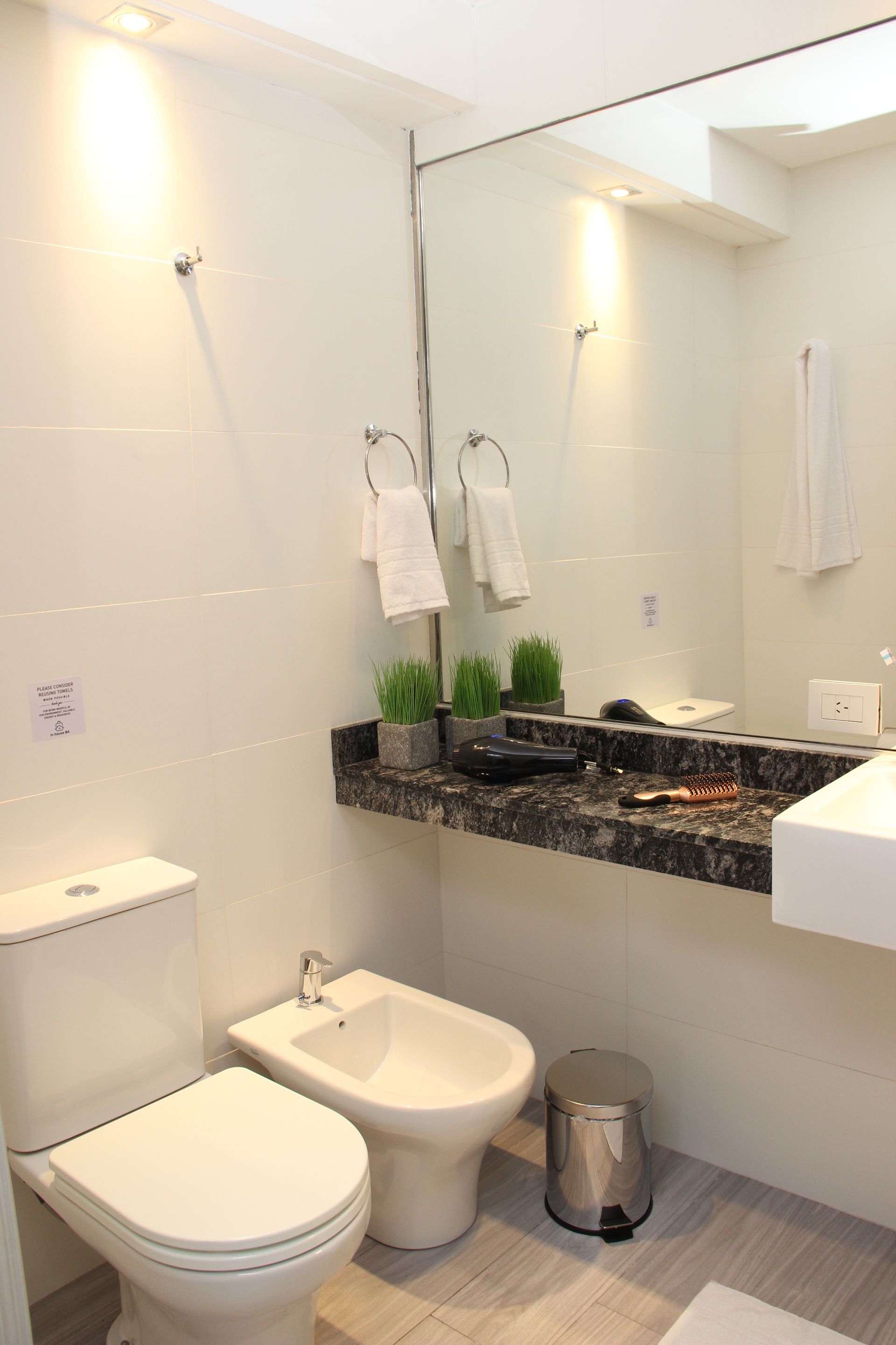 Un baño con inodoro, bidet, lavabo y espejo.