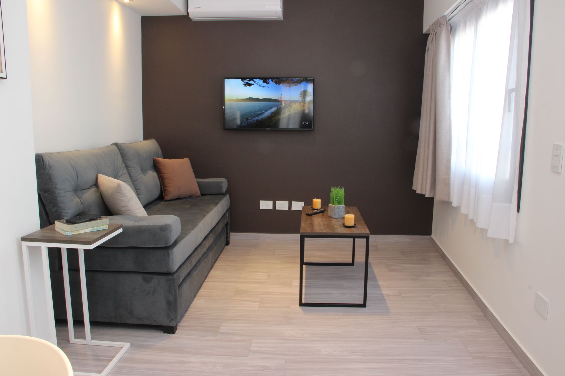 Una sala de estar con un sofá y un televisor en la pared.