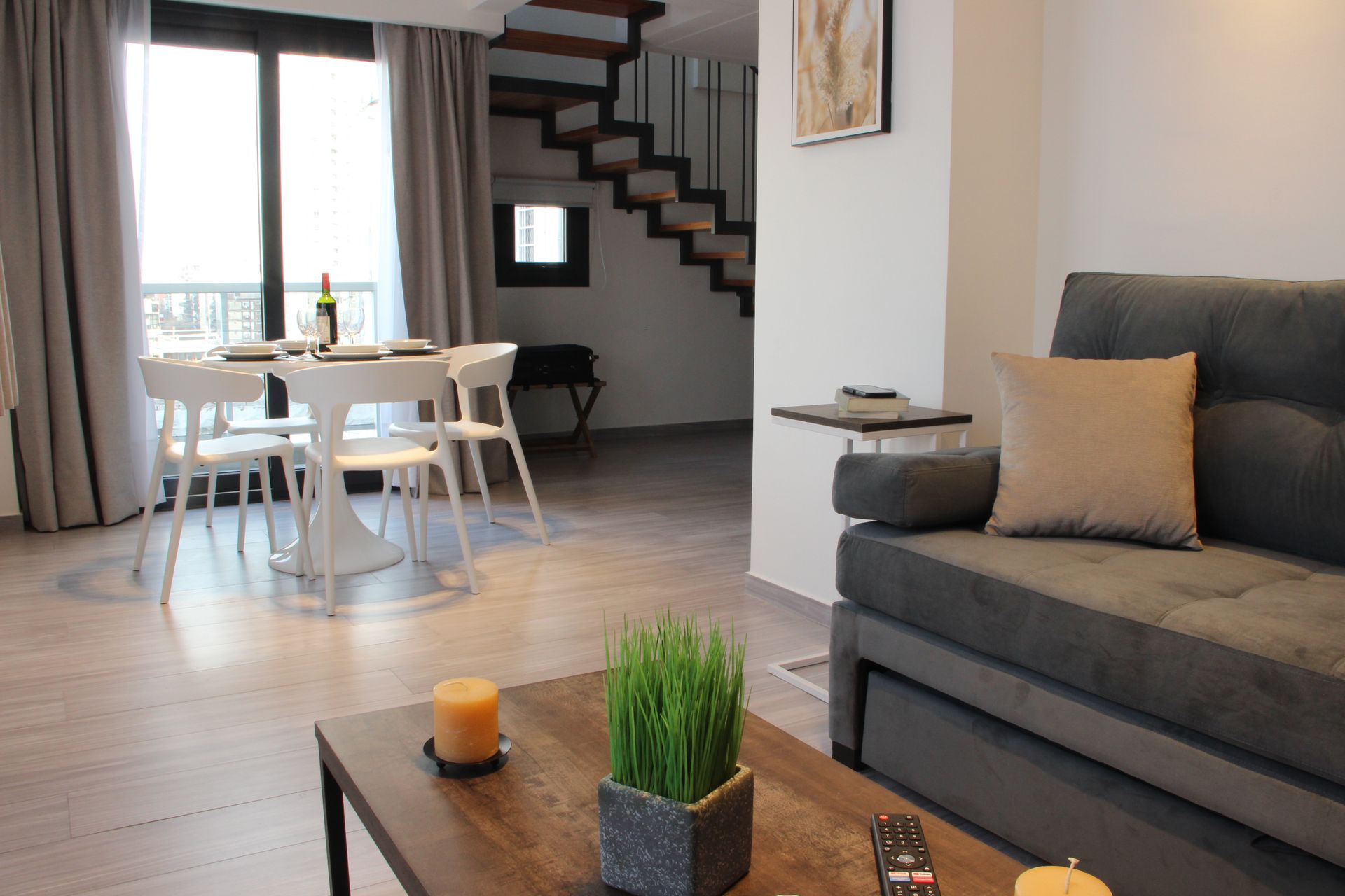 Una sala de estar con sofá, mesa, sillas y escaleras.