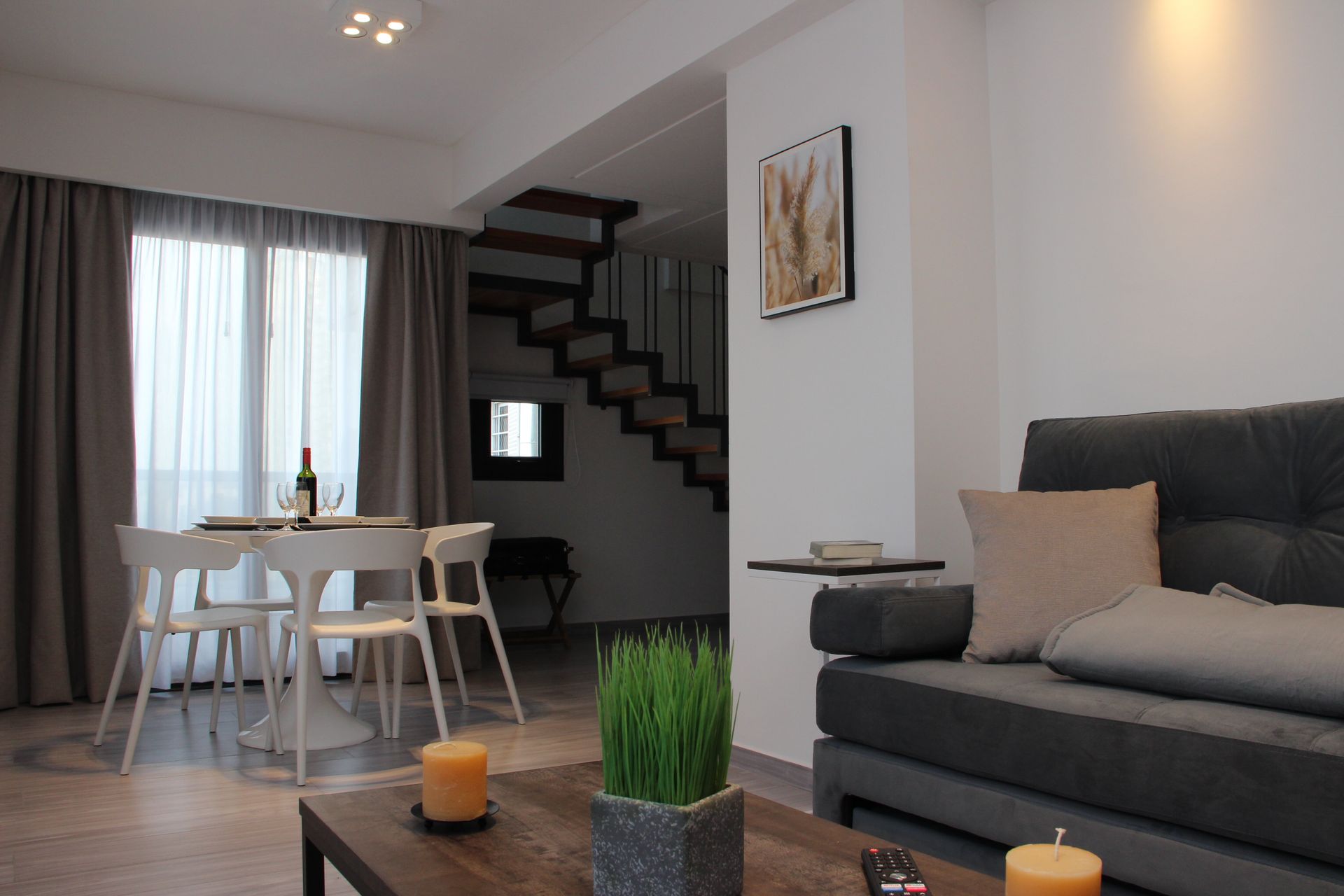 Una sala de estar con sofá, mesa, sillas y escaleras.