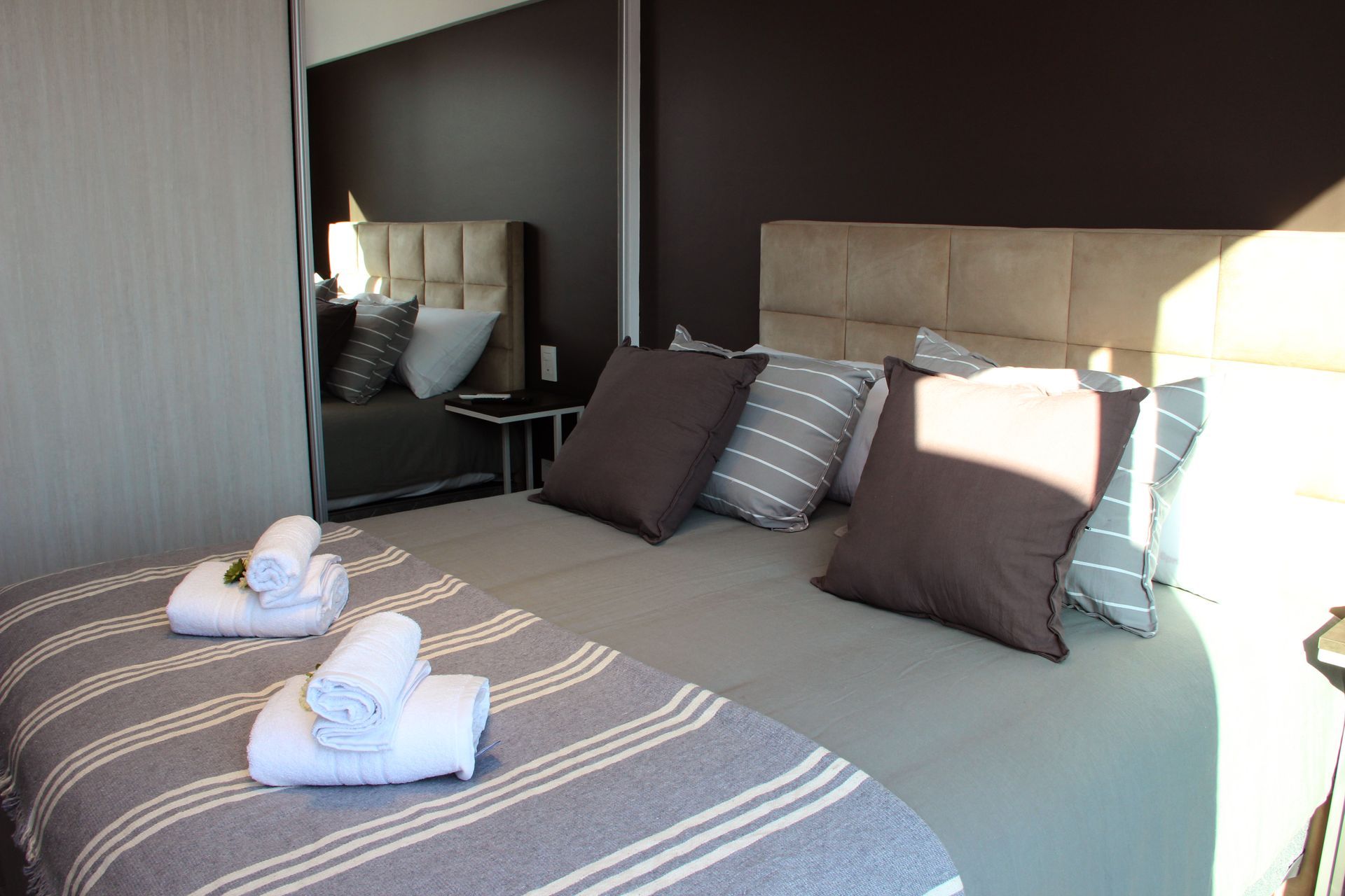 Un dormitorio con una cama, almohadas, toallas y un espejo.