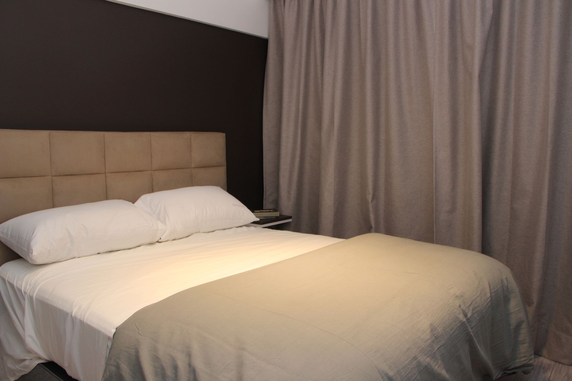 Un dormitorio con una cama, cortinas y un cabecero.