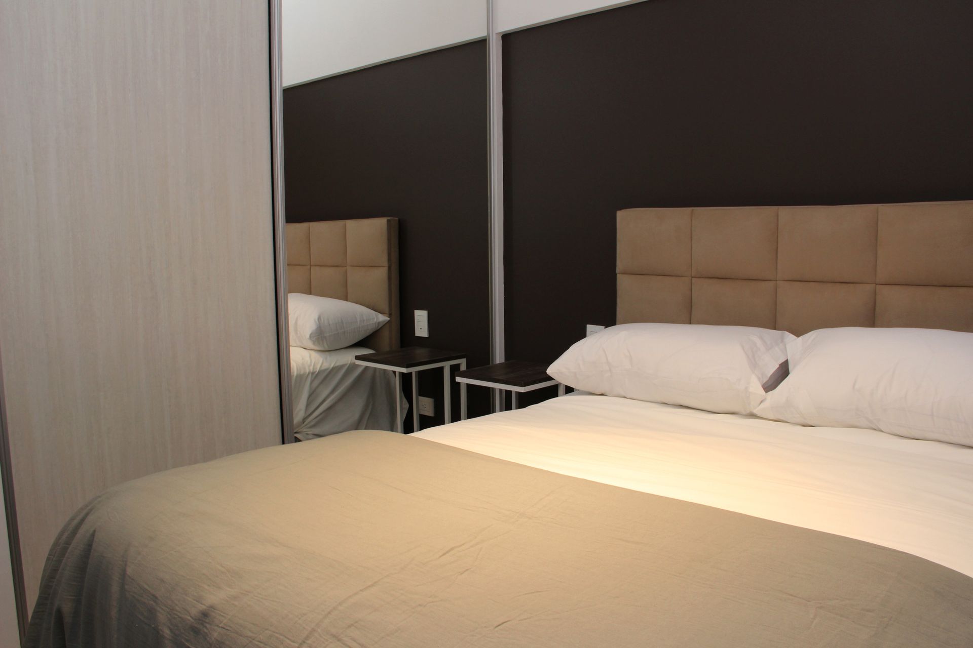 Un dormitorio con una cama, mesitas de noche y un espejo.