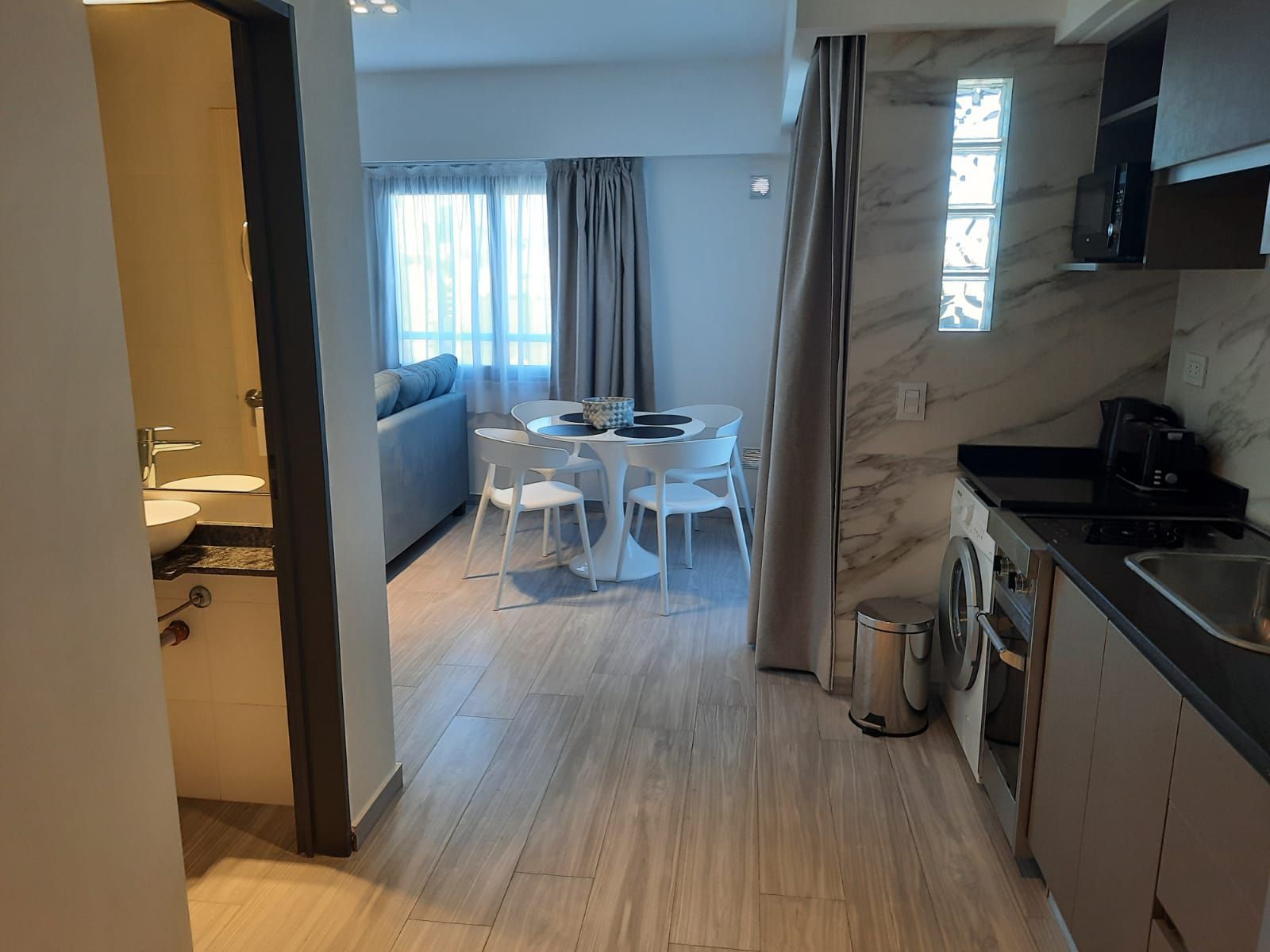 Una cocina con una mesa de comedor y sillas y un fregadero.