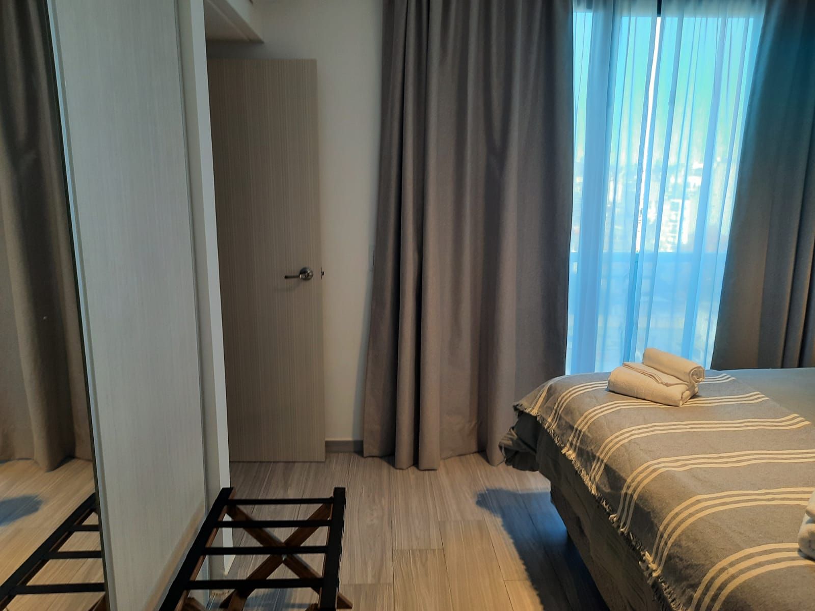 Un dormitorio con una cama, un espejo y una ventana.