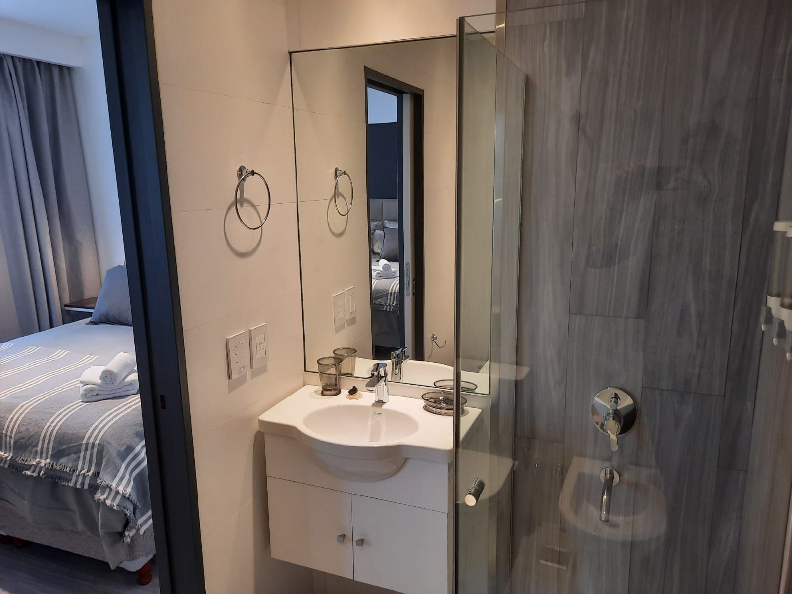 Un baño con lavabo, espejo y ducha.