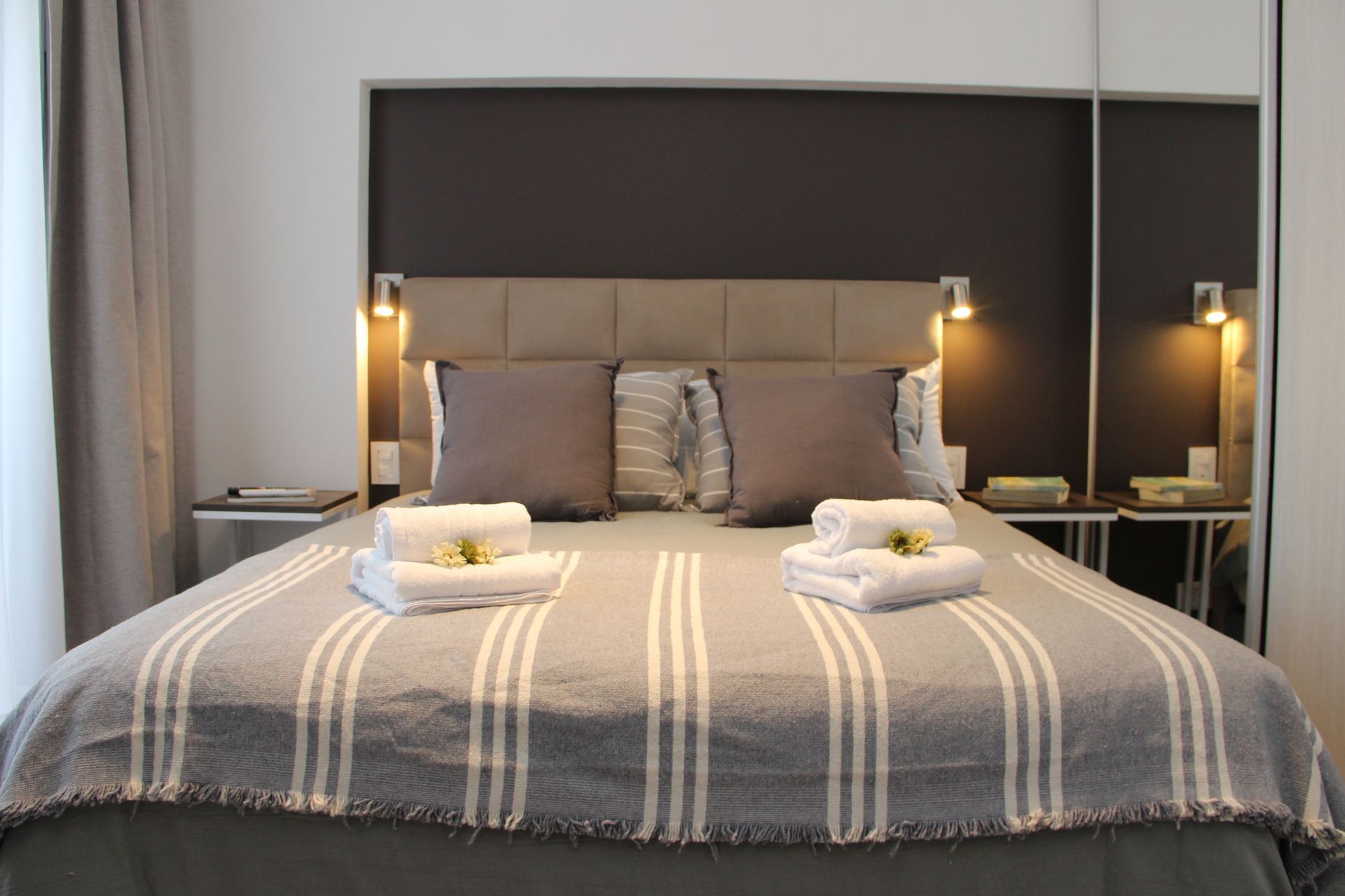 Una cama con una manta a rayas y almohadas en una habitación de hotel.