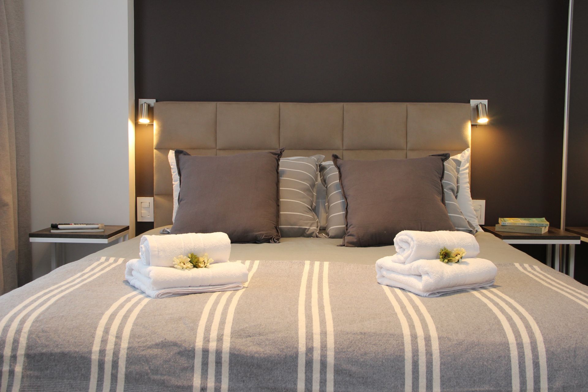 Una cama con una manta a rayas y toallas encima.