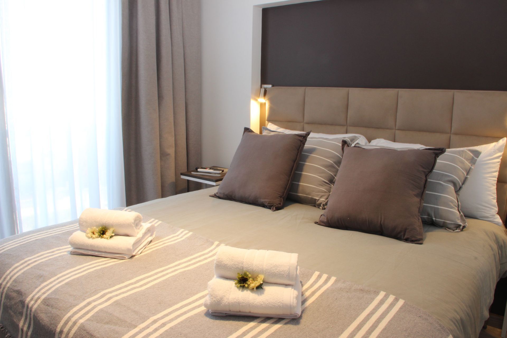 Un dormitorio con una cama, almohadas, toallas y una ventana.