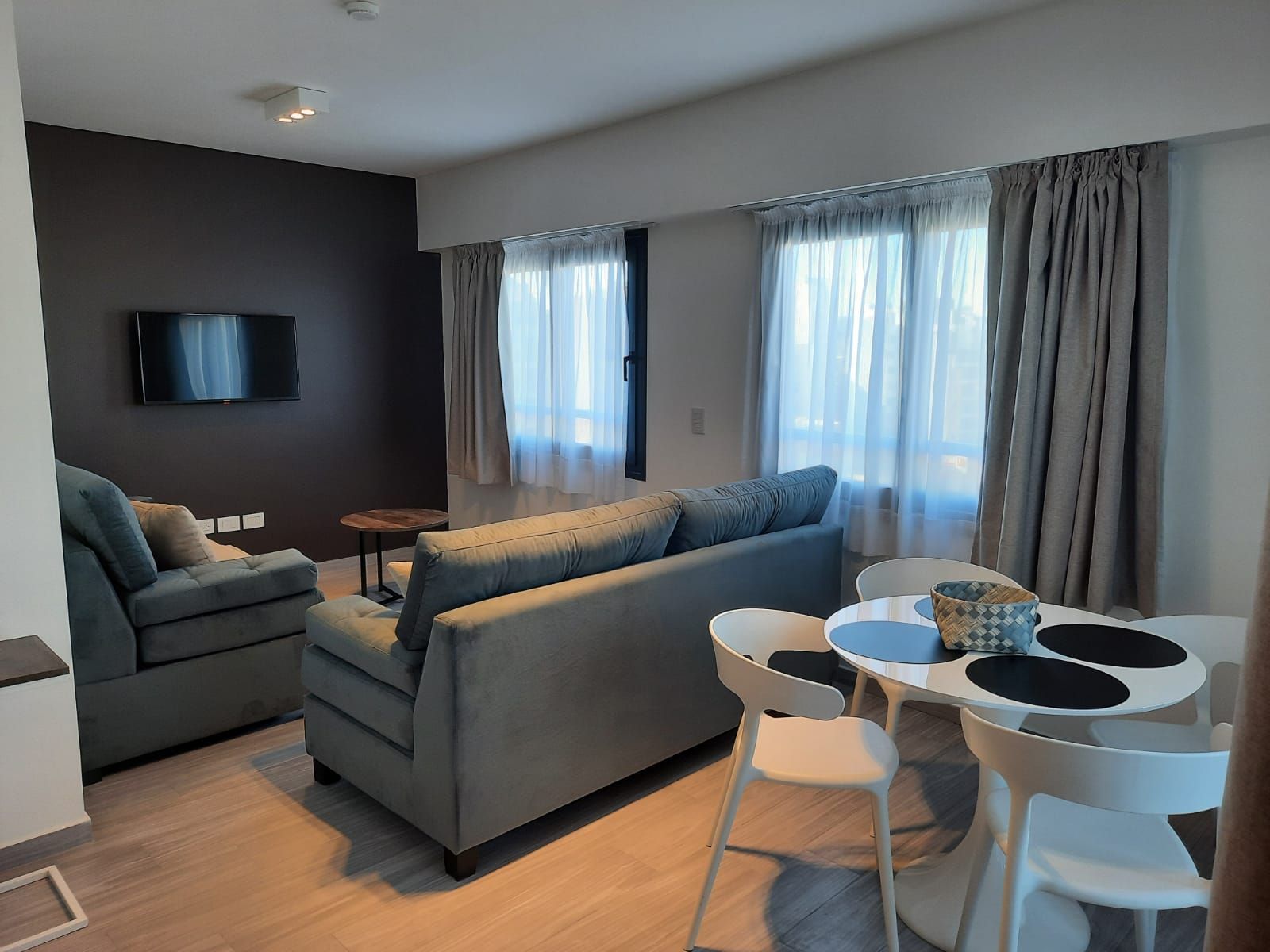 Una sala de estar con sofá, sillas, mesa y televisión.