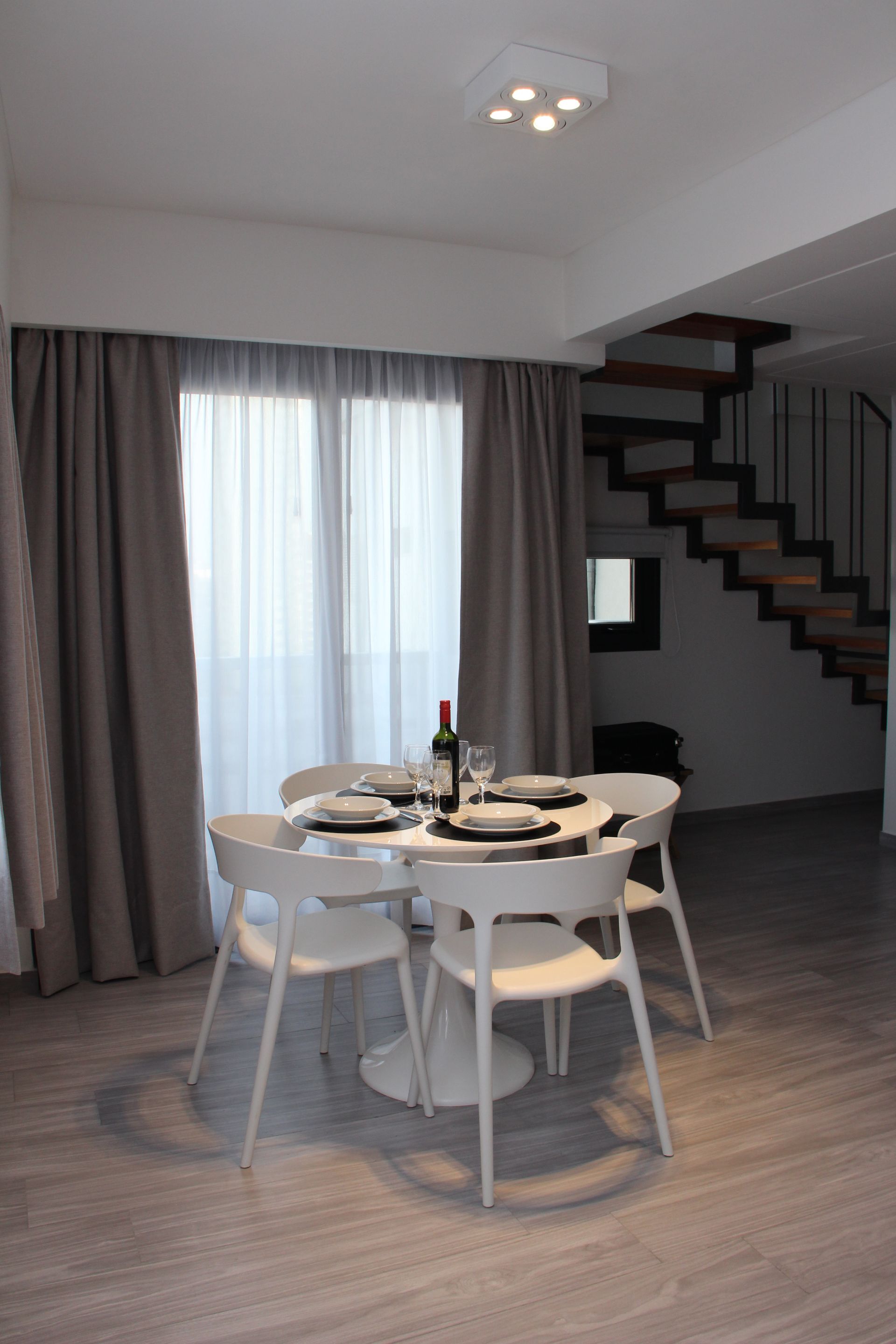 Un comedor con mesa y sillas y una escalera.