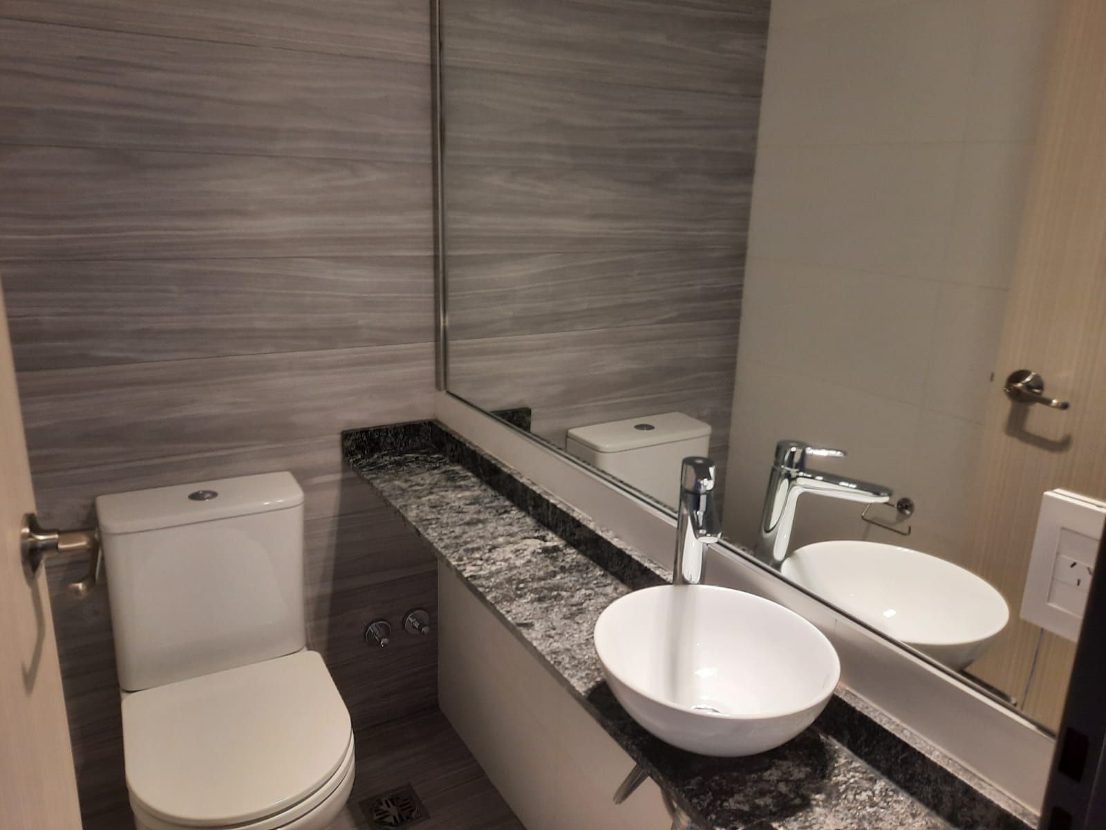 Un baño con inodoro, lavabo y espejo.