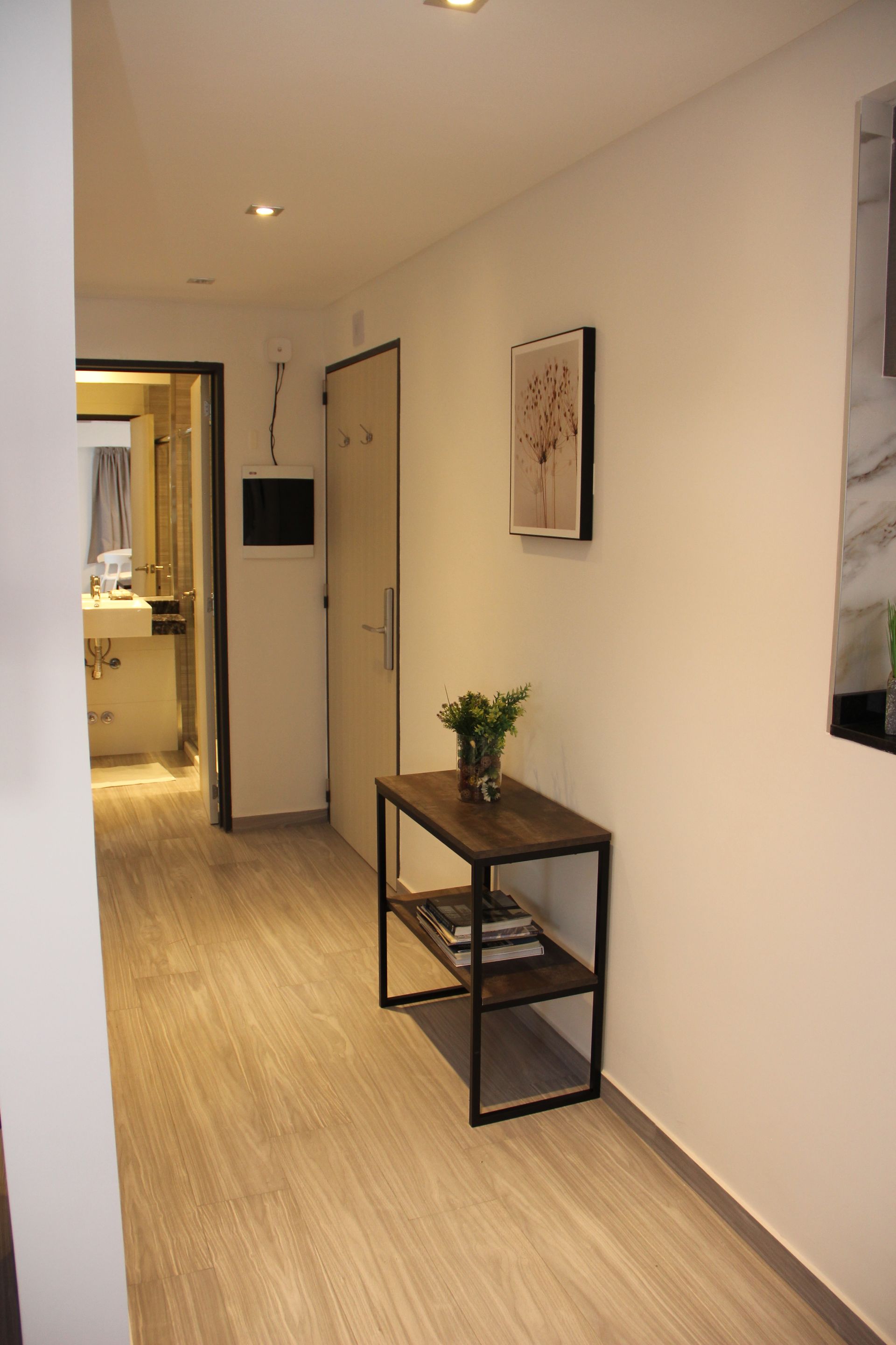 Un pasillo con una mesa y un cuadro en la pared.