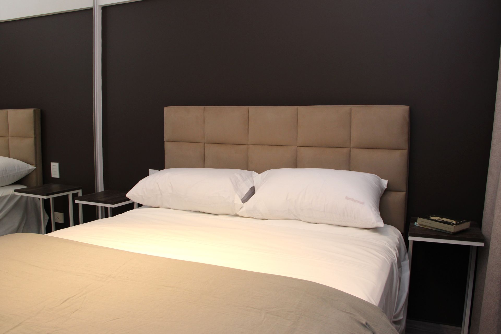 Una cama con sábanas blancas y almohadas en un dormitorio.