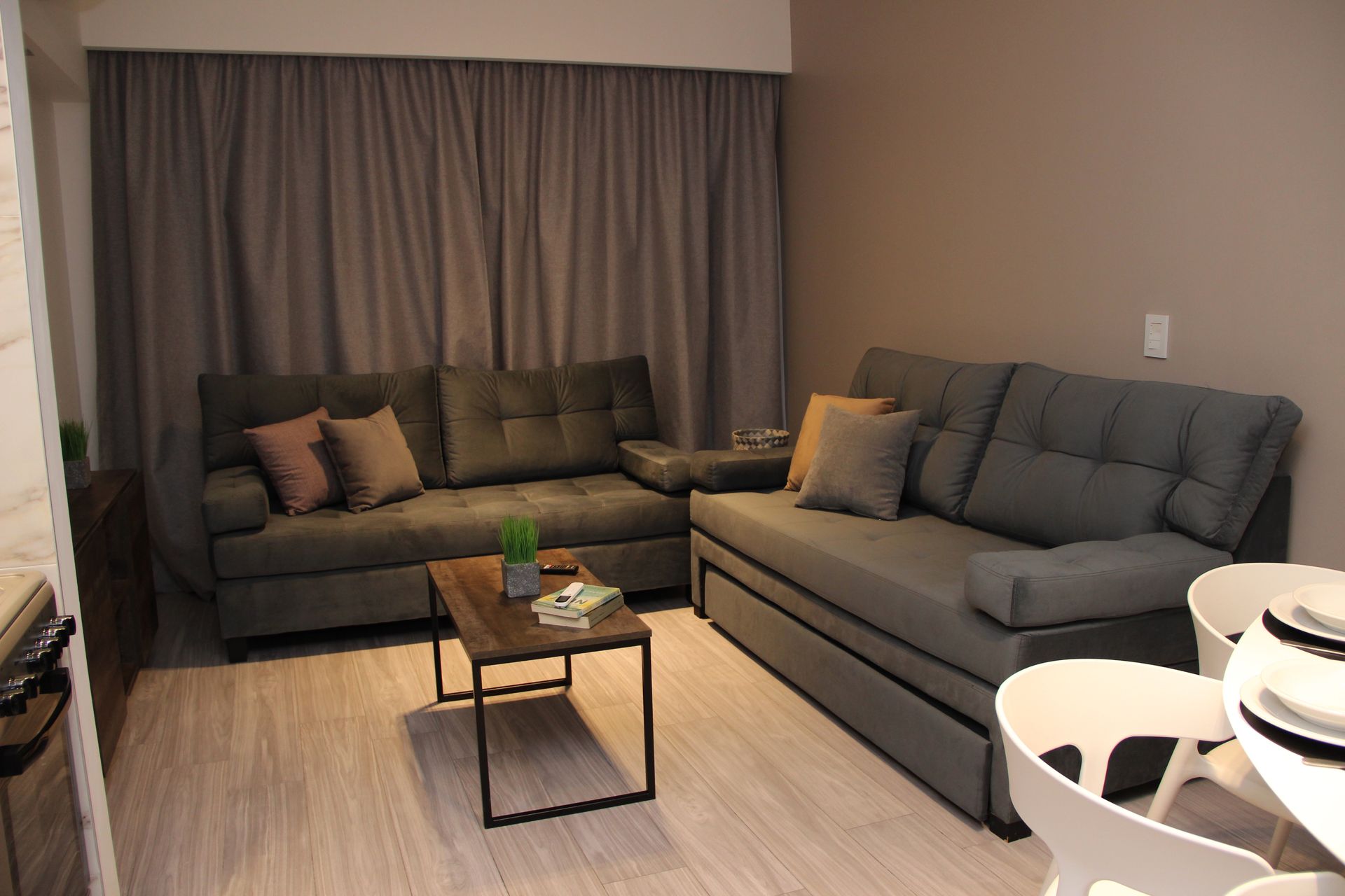 Una sala de estar con sofá, mesa, sillas y cortinas.