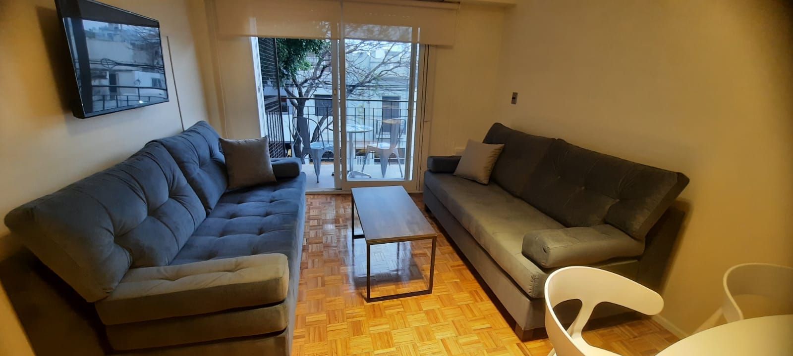 Una sala de estar con sofá, mesa y televisión.