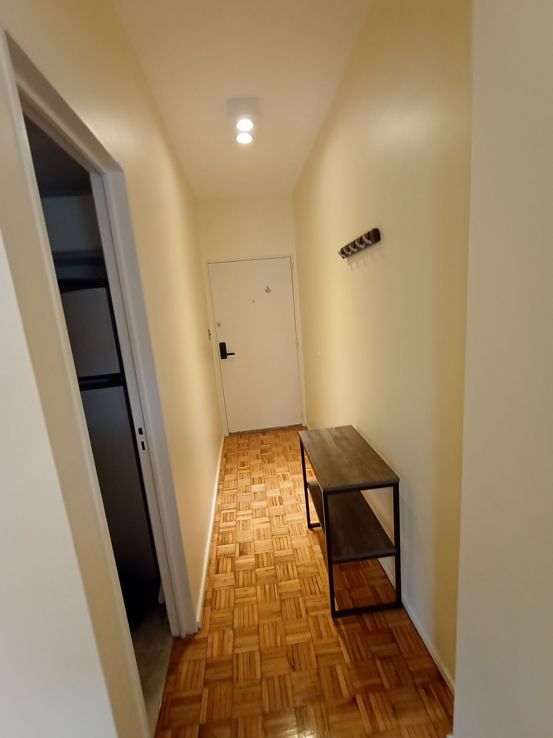 Un pasillo con suelo de madera y una mesa en el medio.