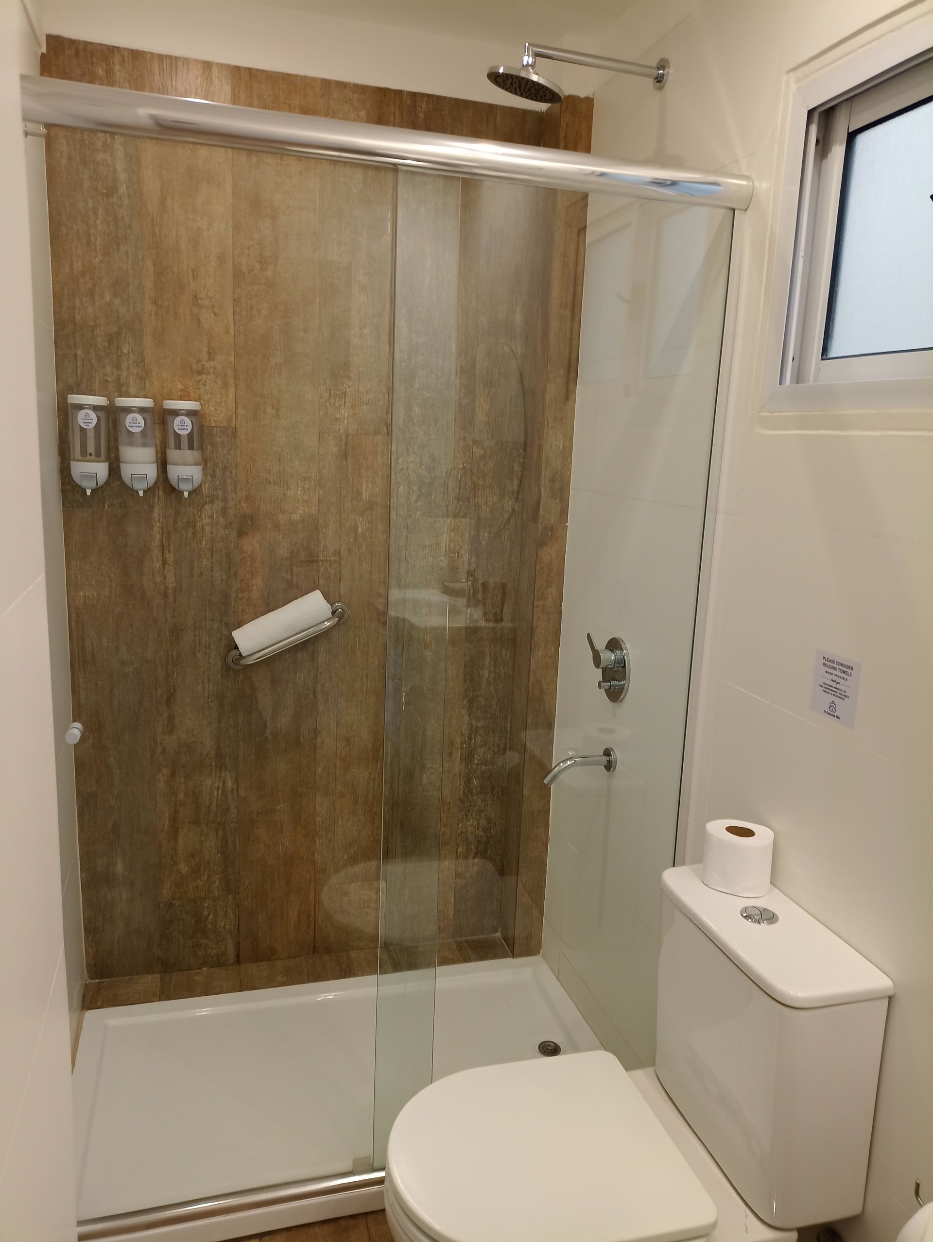 Un baño con inodoro, ducha y ventana.