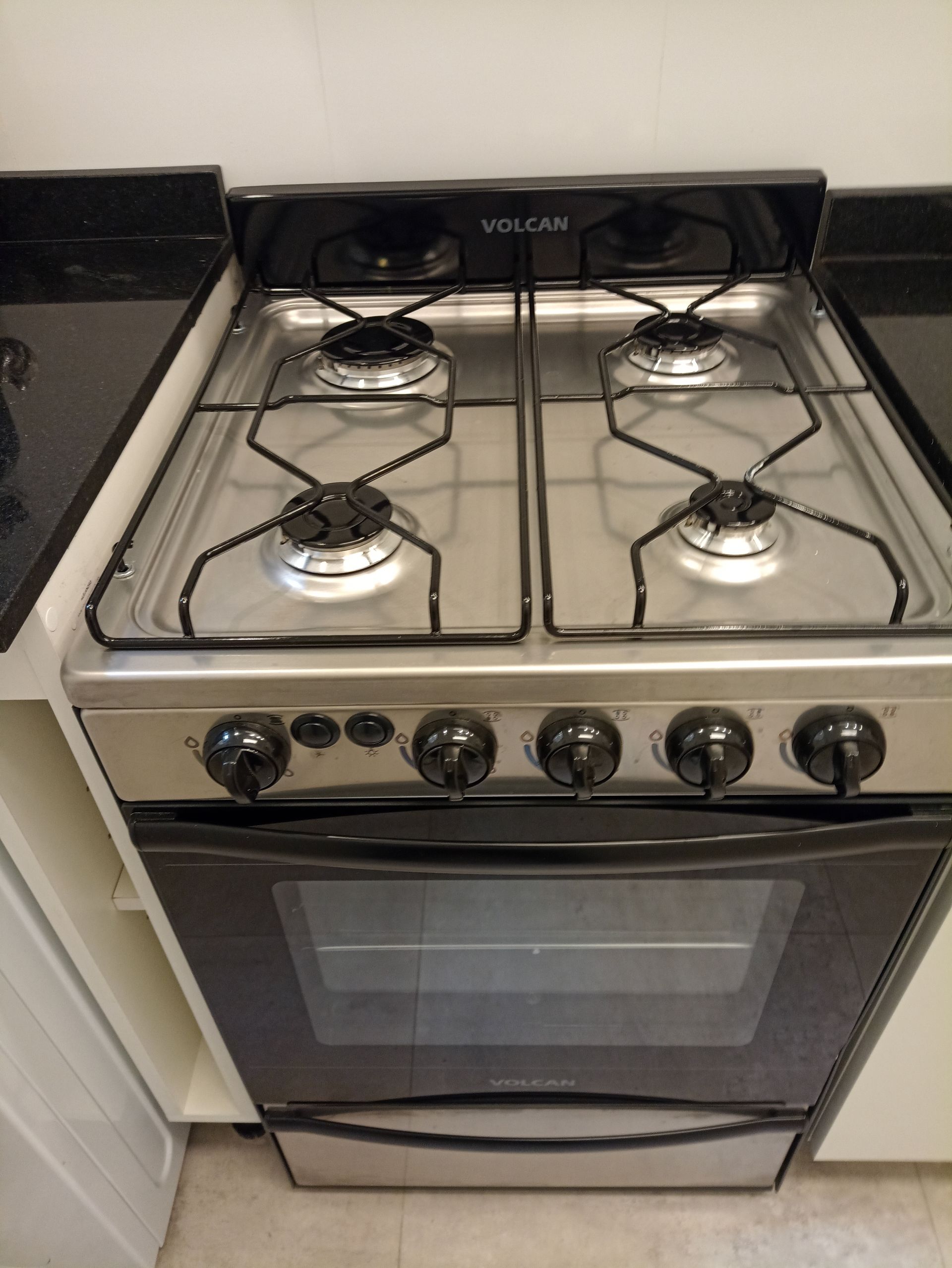 Una estufa con cuatro quemadores y un horno negro en una cocina.