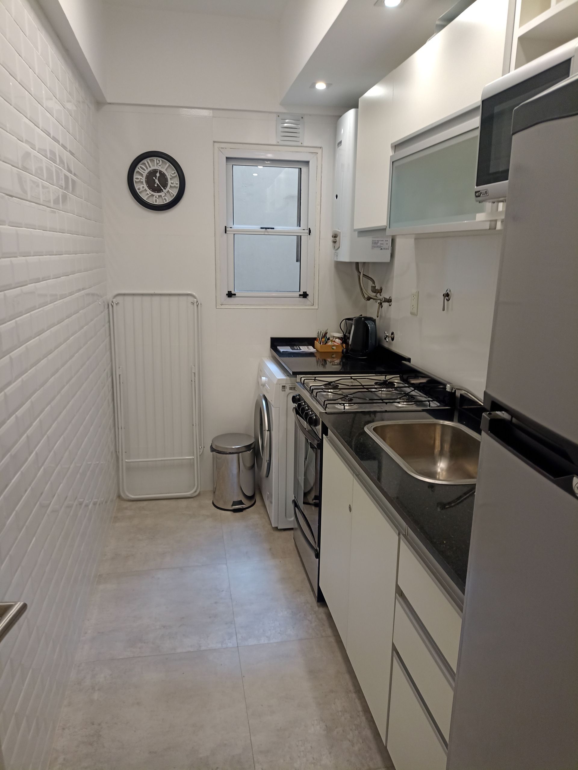 Una cocina con refrigerador, estufa, fregadero y microondas.