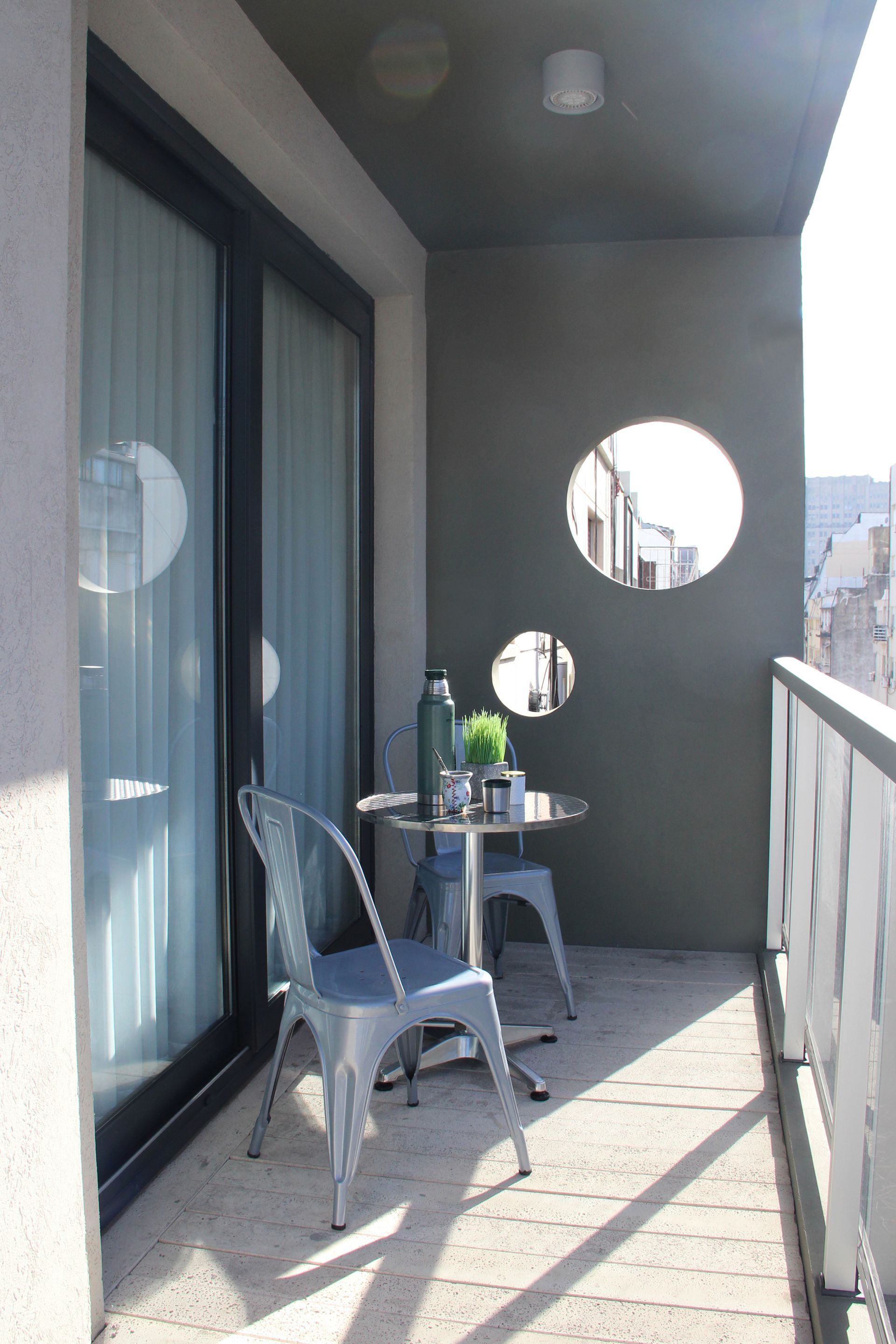 Un balcón con una mesa y sillas y una ventana.