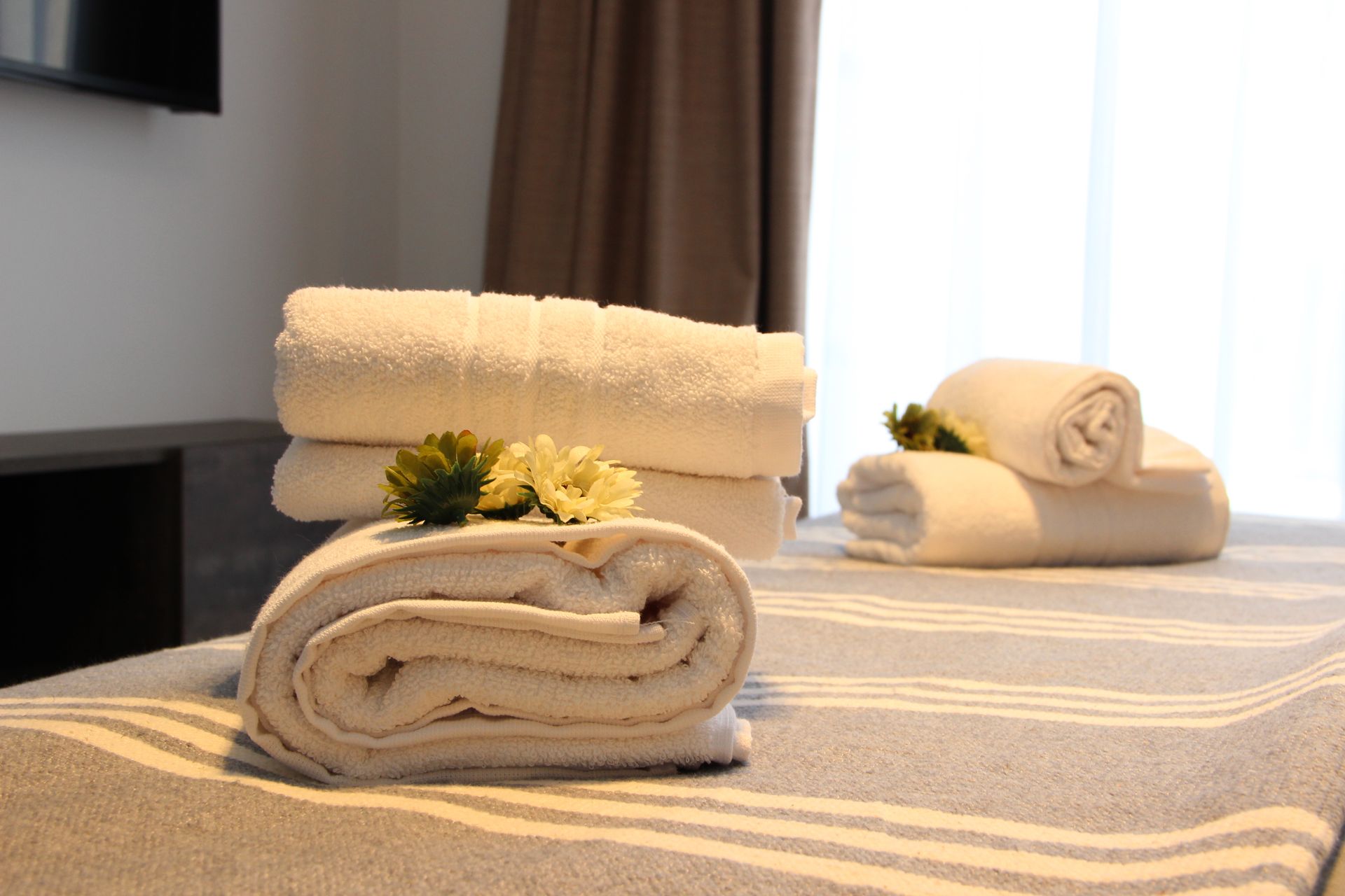 Una cama con toallas y flores en una habitación de hotel.