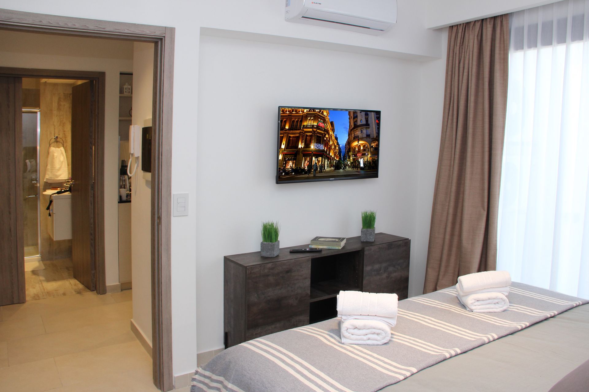 Un dormitorio con una cama y un televisor en la pared.