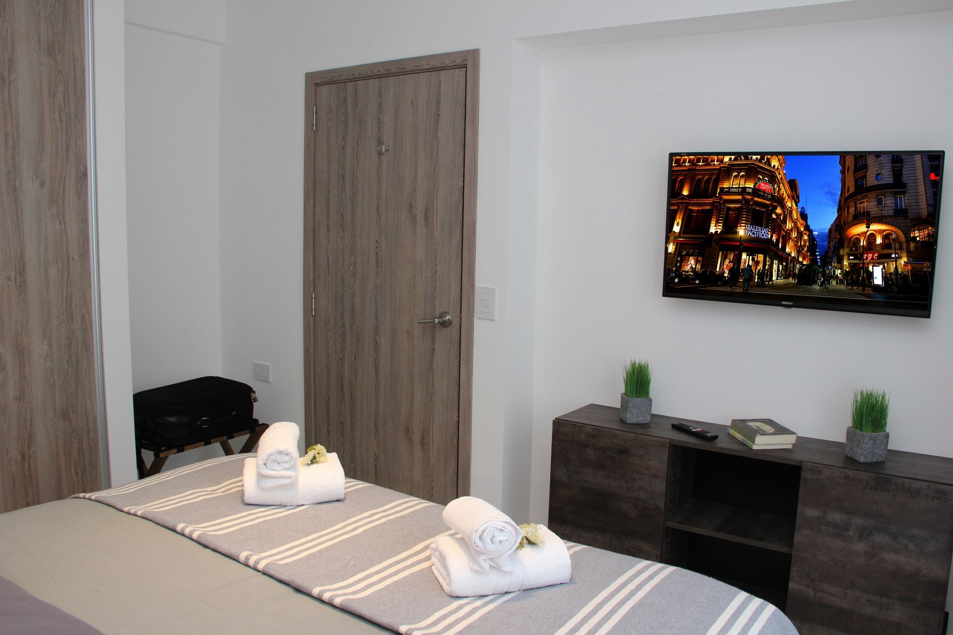 Un dormitorio con una cama y un televisor de pantalla plana en la pared.