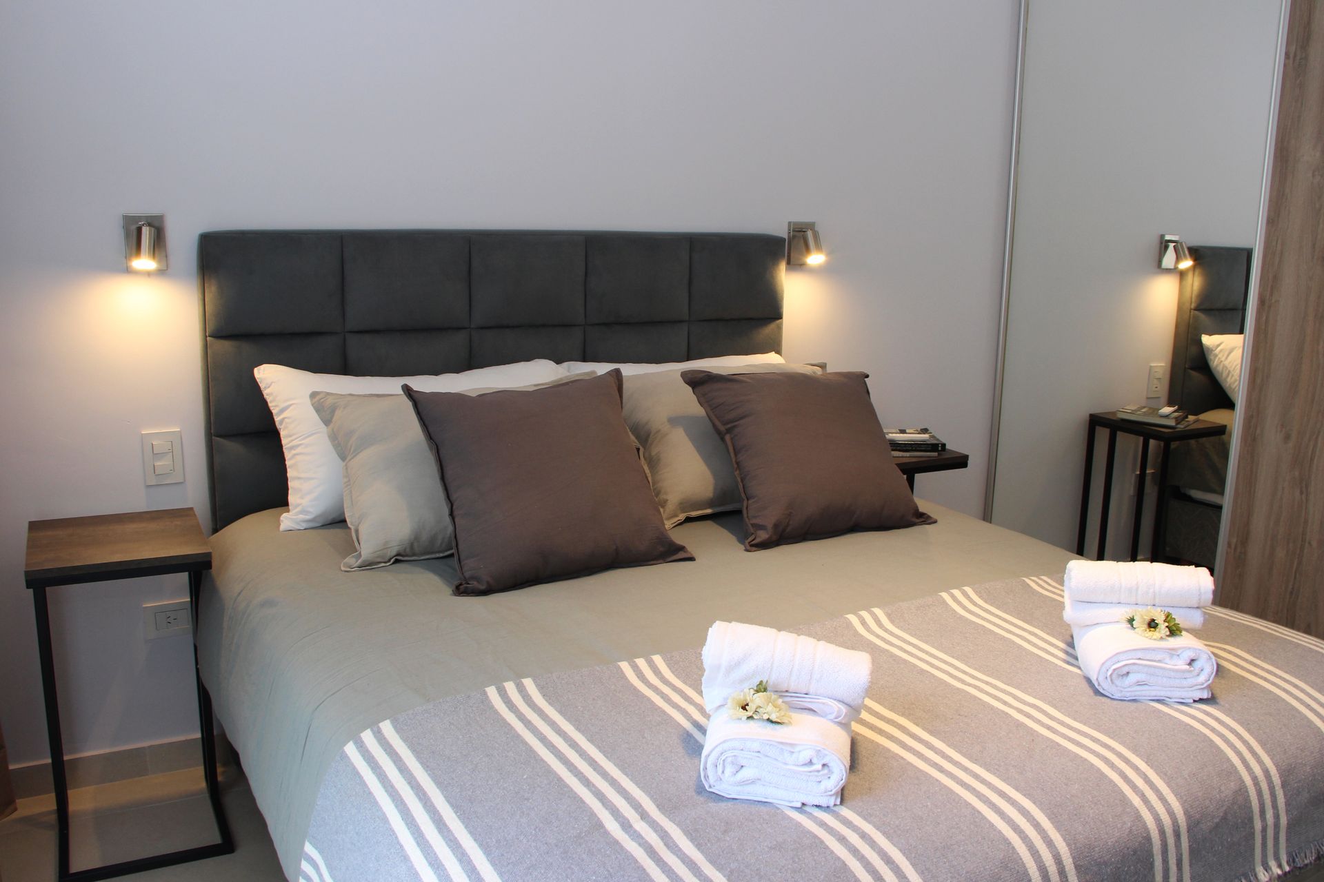 Una cama con una manta a rayas y almohadas en un dormitorio.