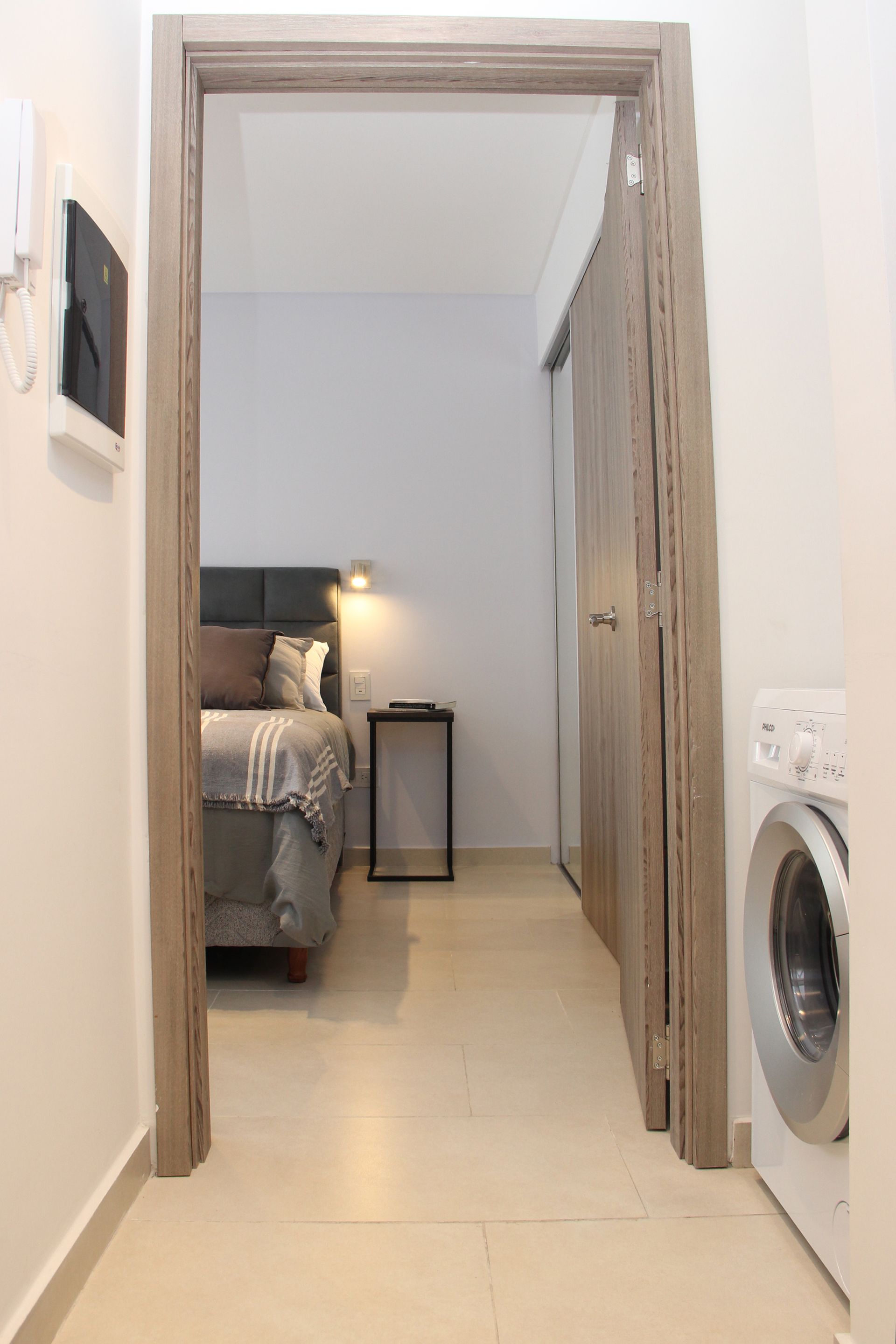 Un pasillo que conduce a un dormitorio con lavadora y secadora.