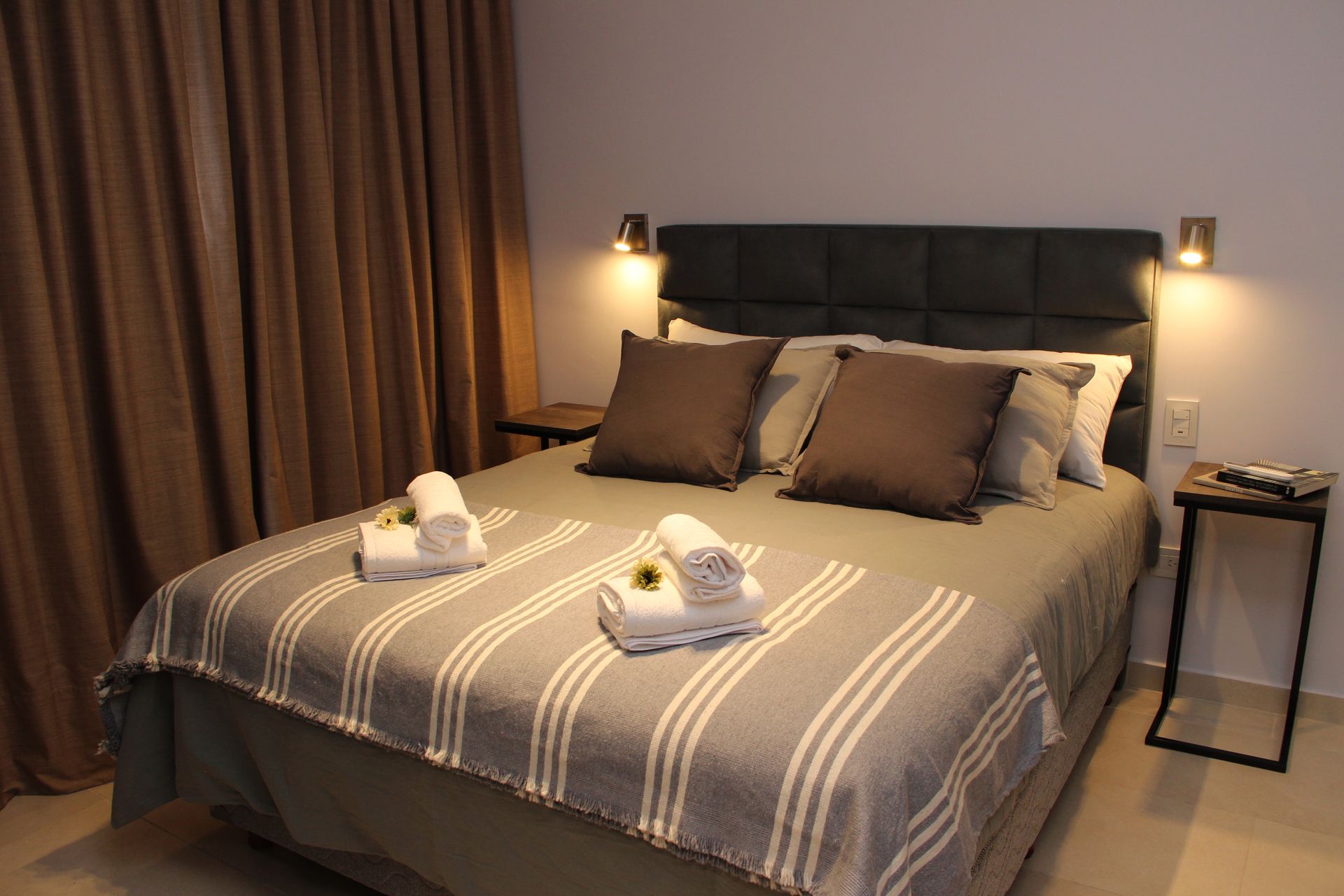 Una cama con una manta a rayas y almohadas en una habitación de hotel.