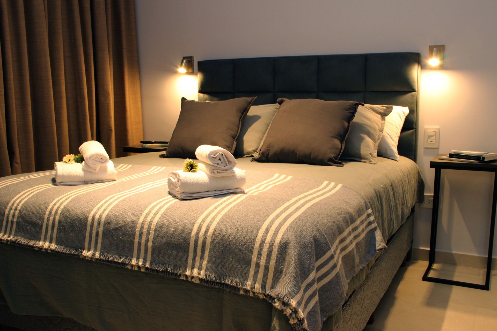 Una cama con una manta a rayas y almohadas en una habitación de hotel.