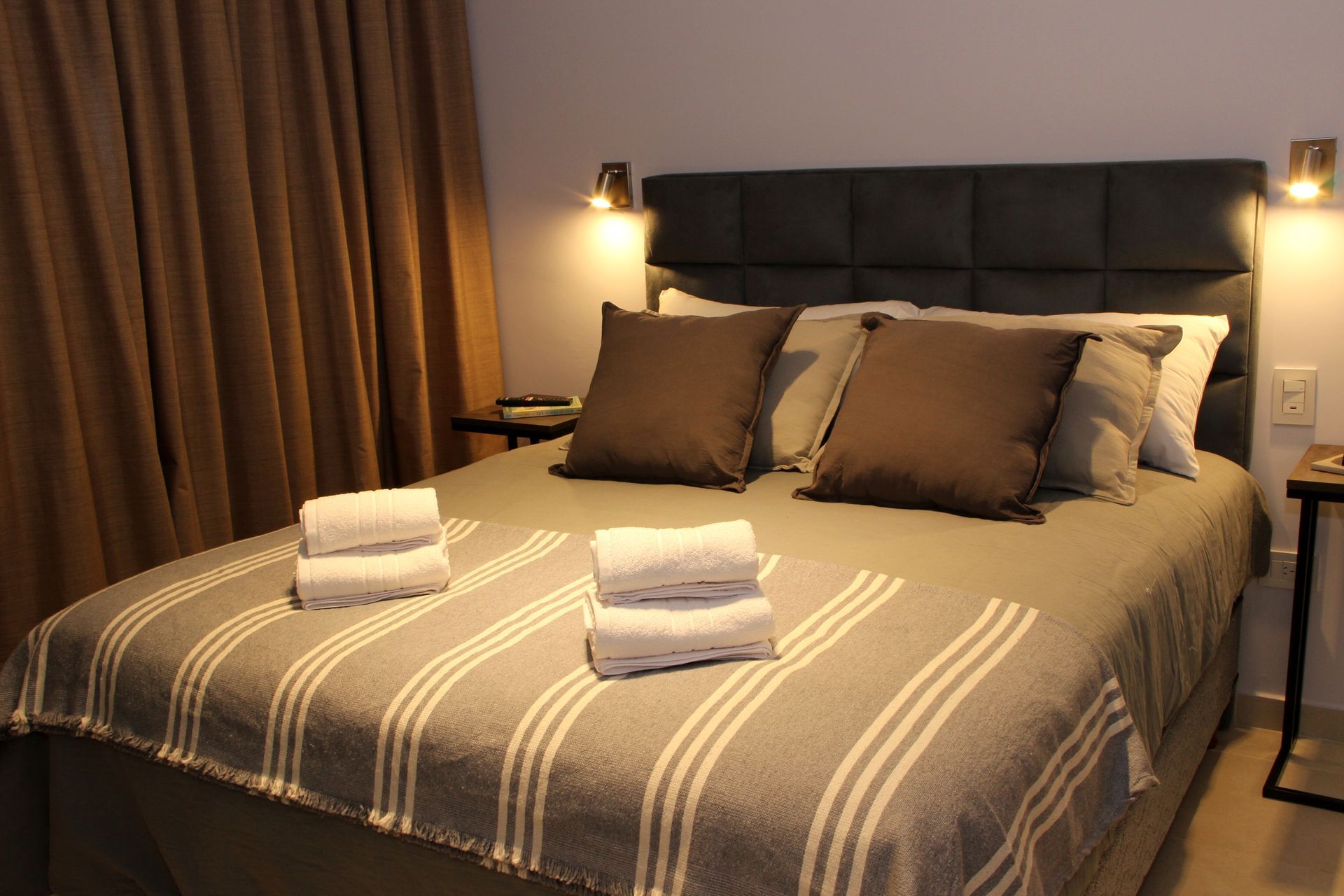 Una cama con una manta a rayas y almohadas en una habitación de hotel.