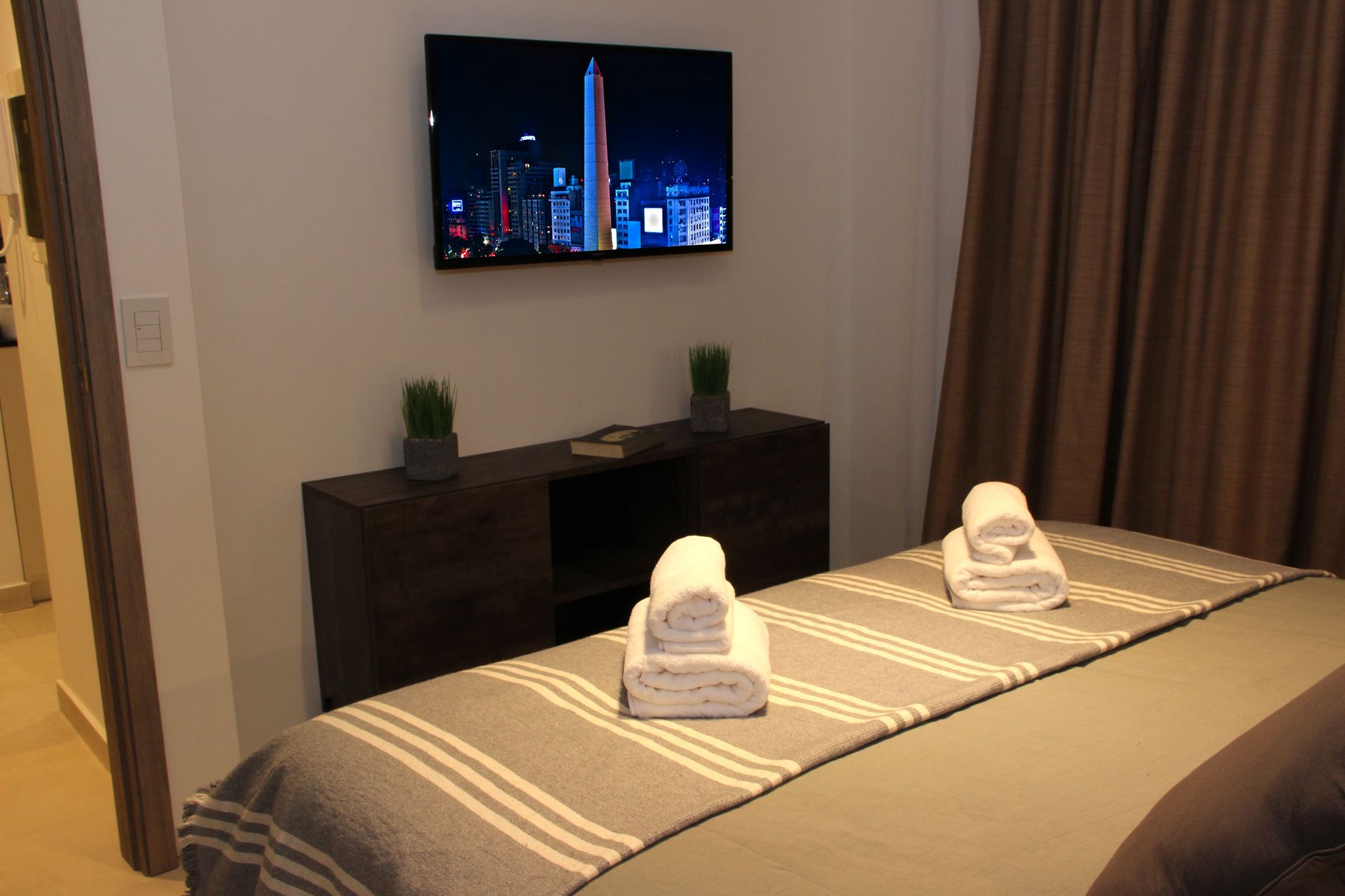 Un dormitorio con una cama y un televisor de pantalla plana en la pared.