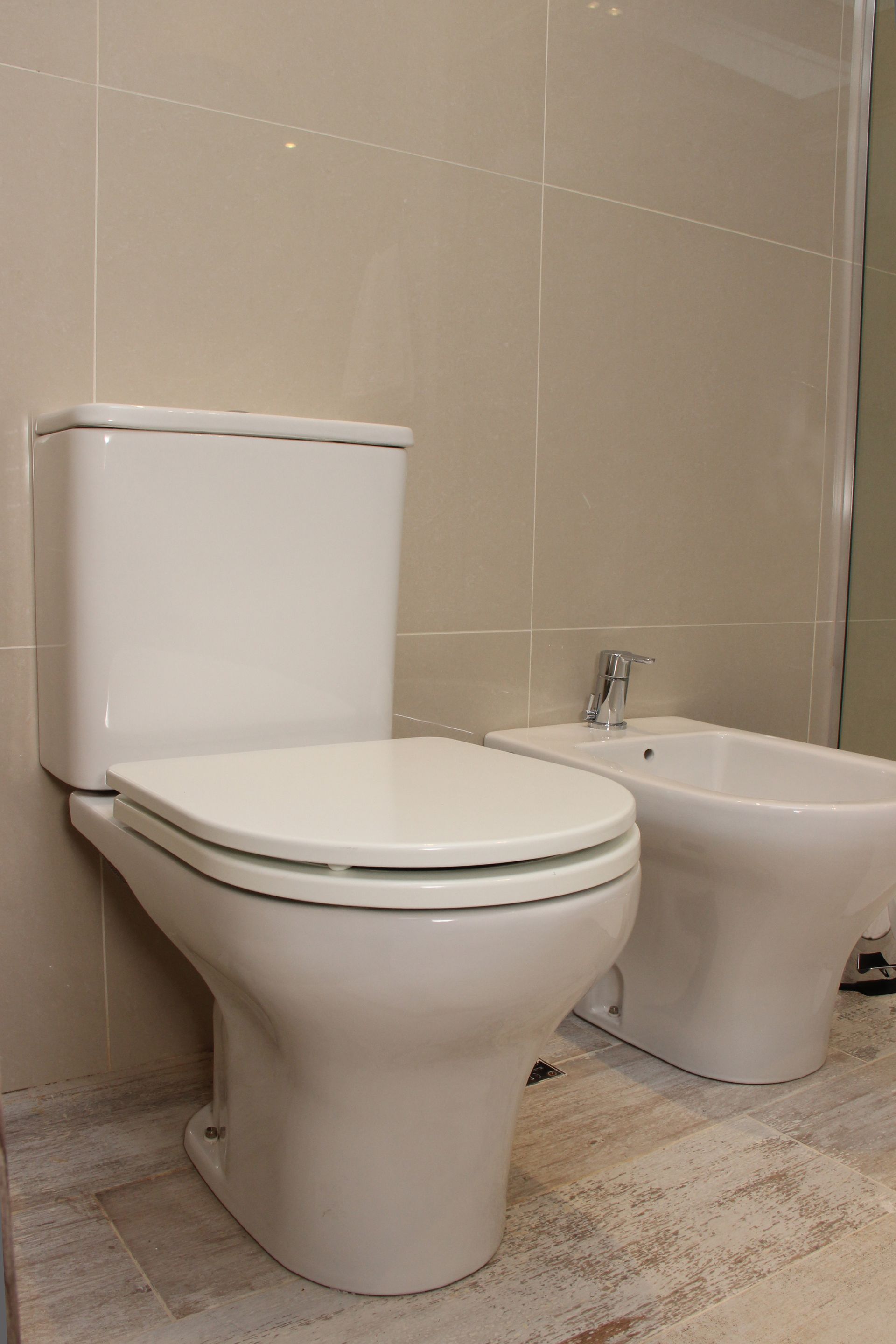 Un baño con dos inodoros y un bidé.