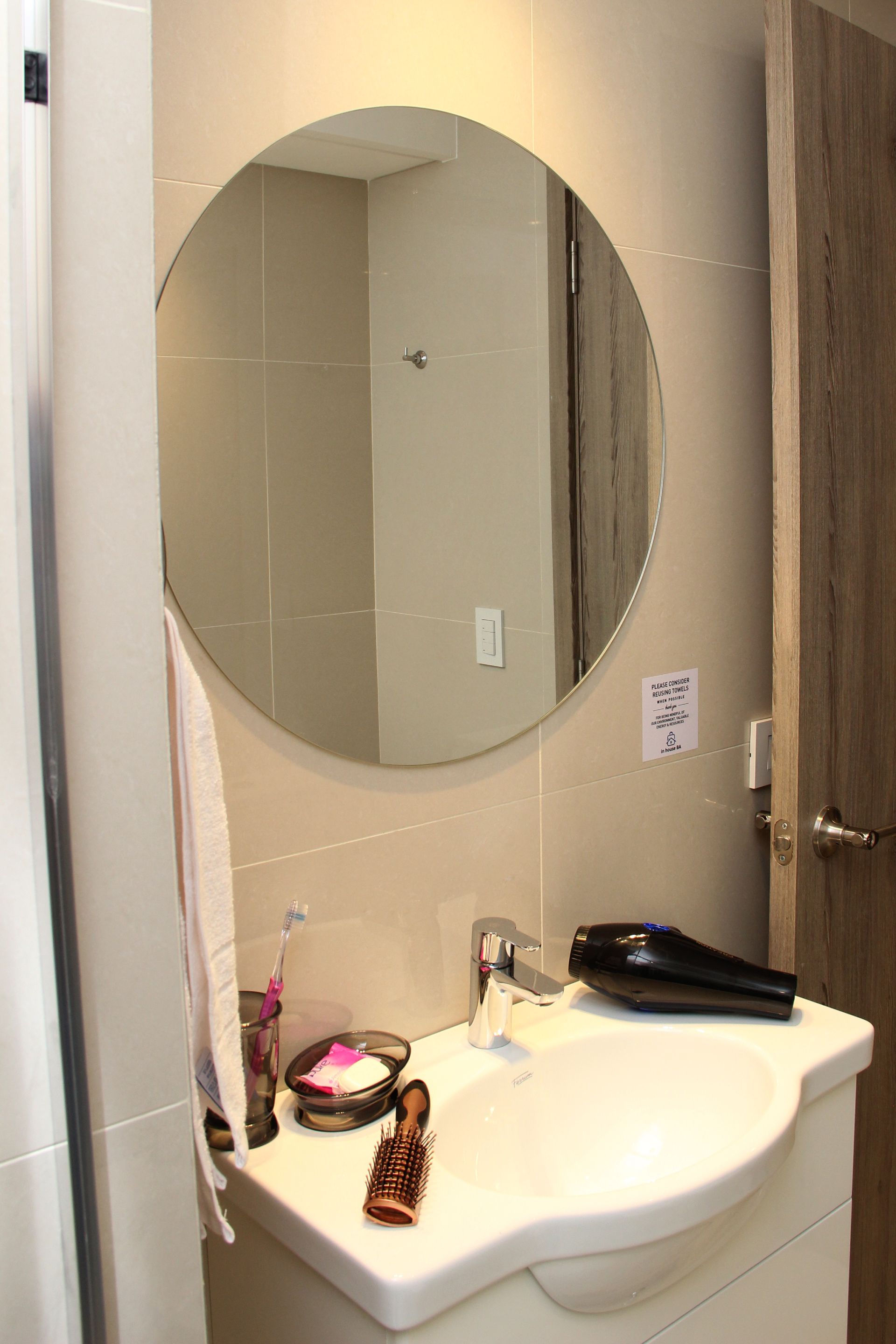 Un baño con lavabo y espejo redondo.